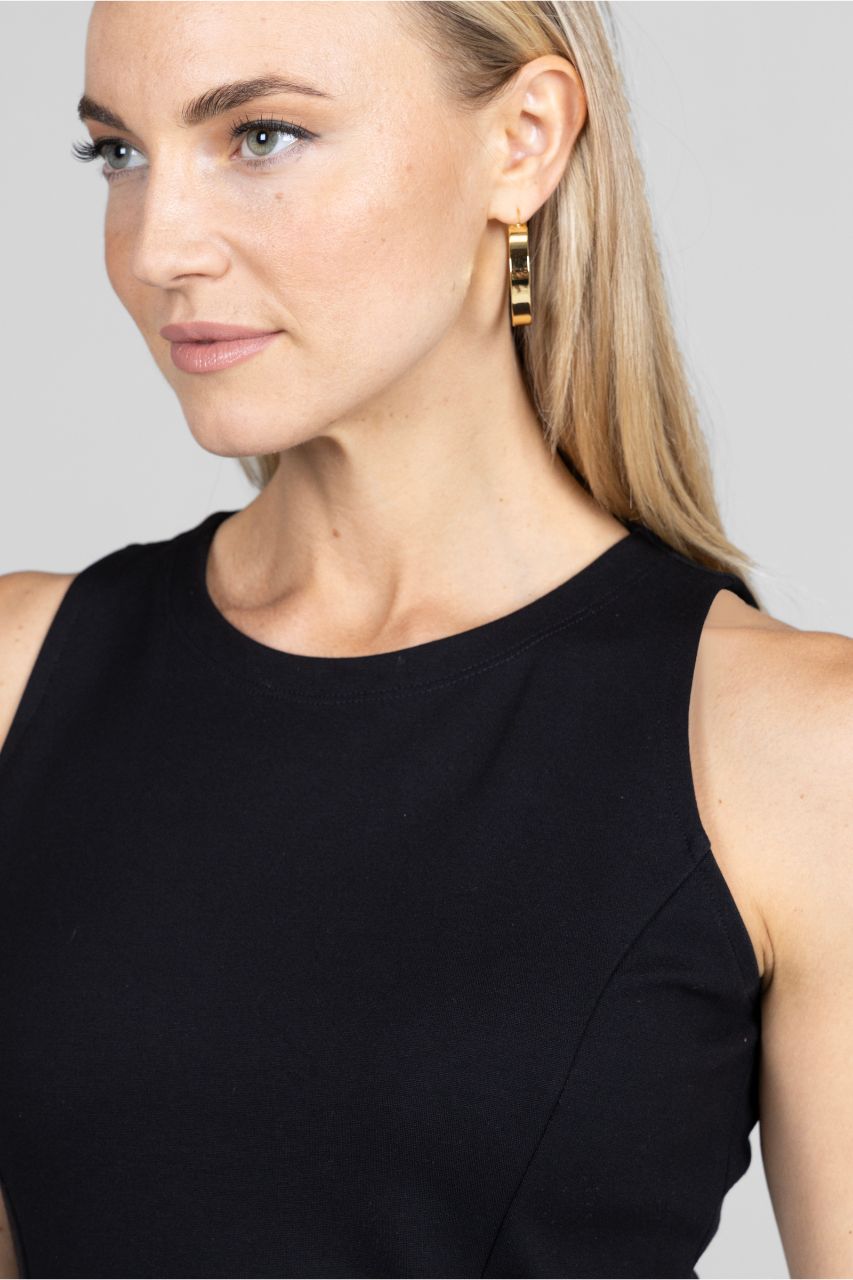 Woman wearing gold hoop earrings with a plain background