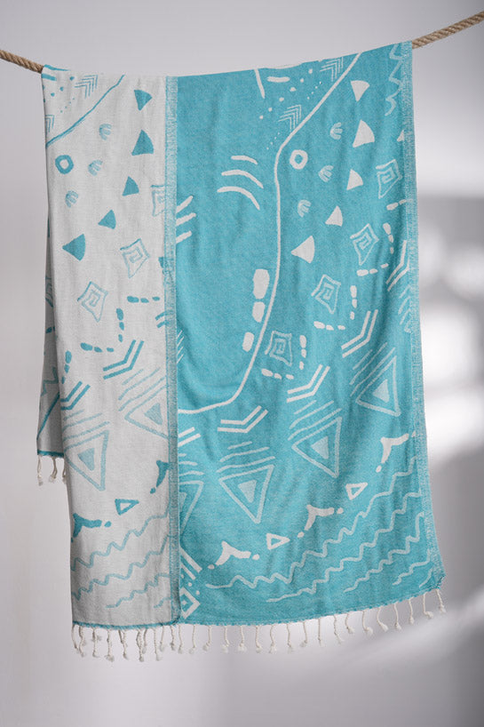 Turquoise and white patterned towel hanging on a line against a light background