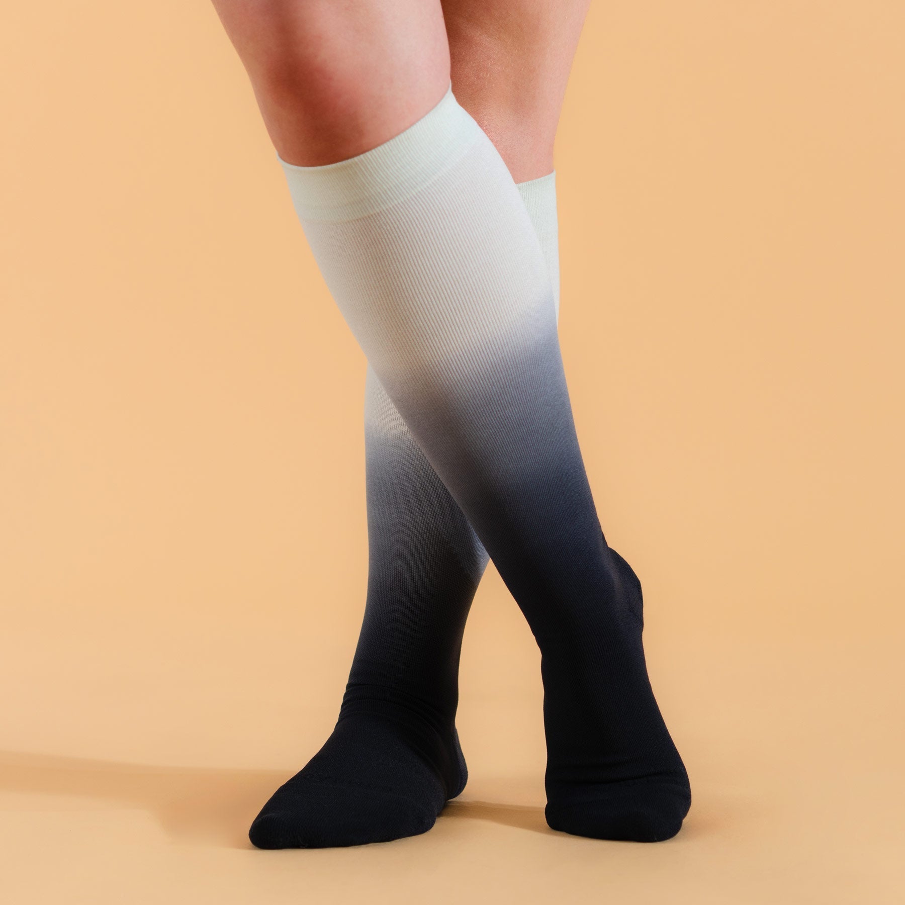 Knee-high gradient socks transitioning from light green to black on a beige background