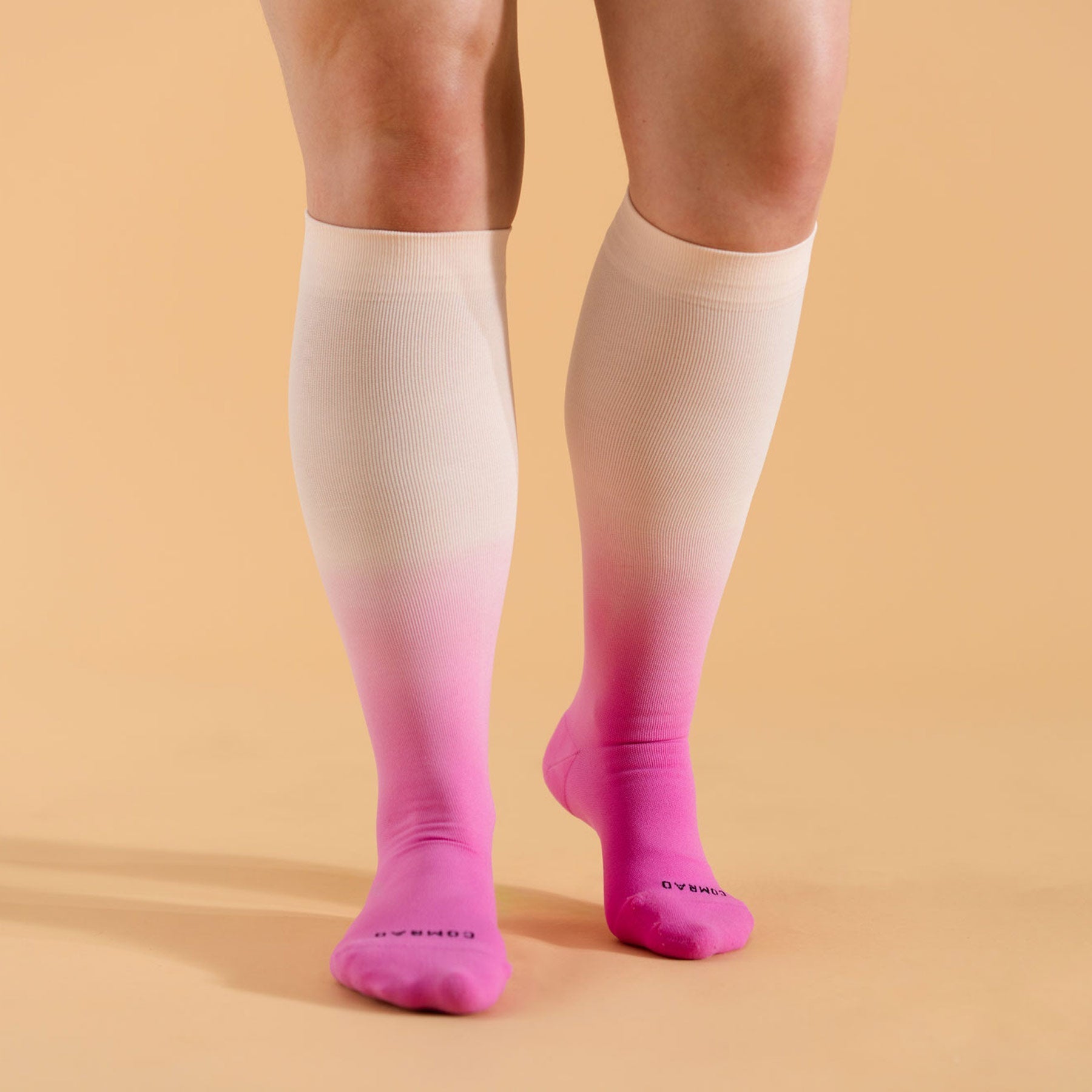 Knee-high socks with a gradient from pink to white on a beige background