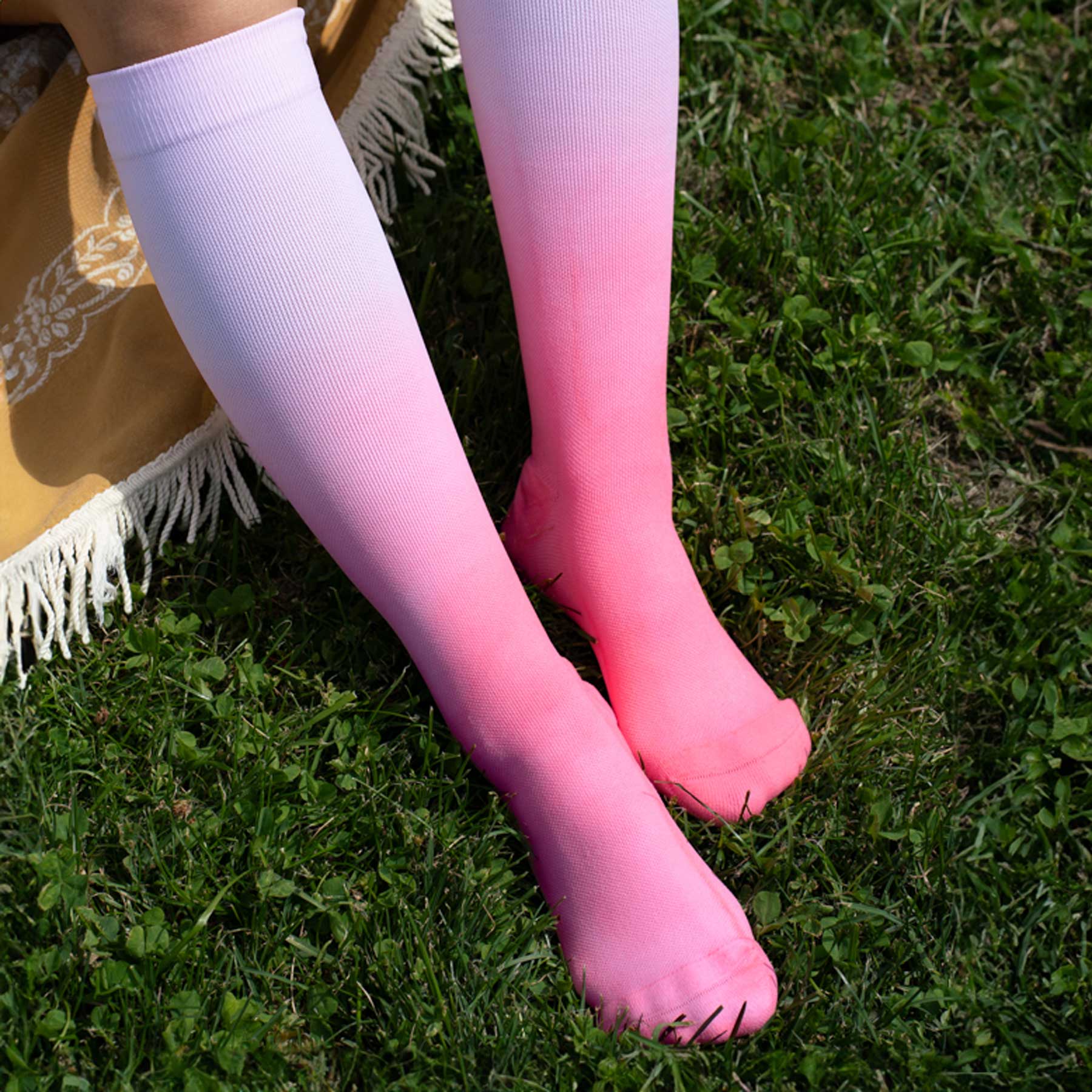 Person wearing pink and white gradient knee-high socks on grass