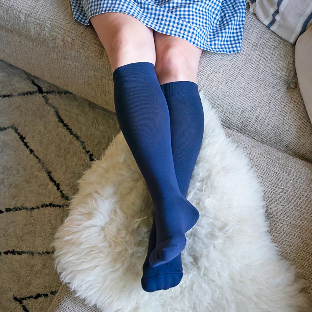 Person wearing blue knee-high socks on a textured rug