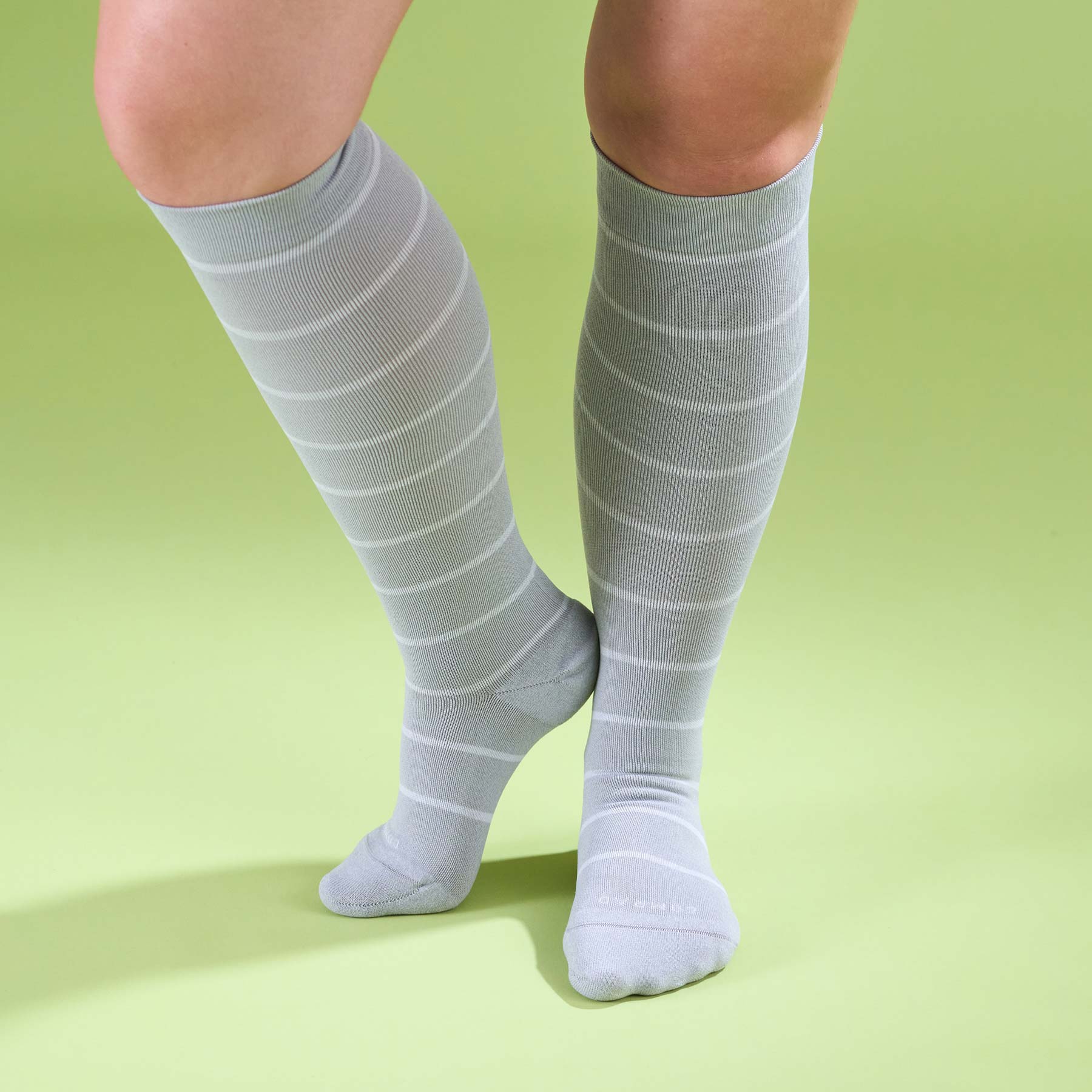Gray knee-high socks with white stripes on a green background