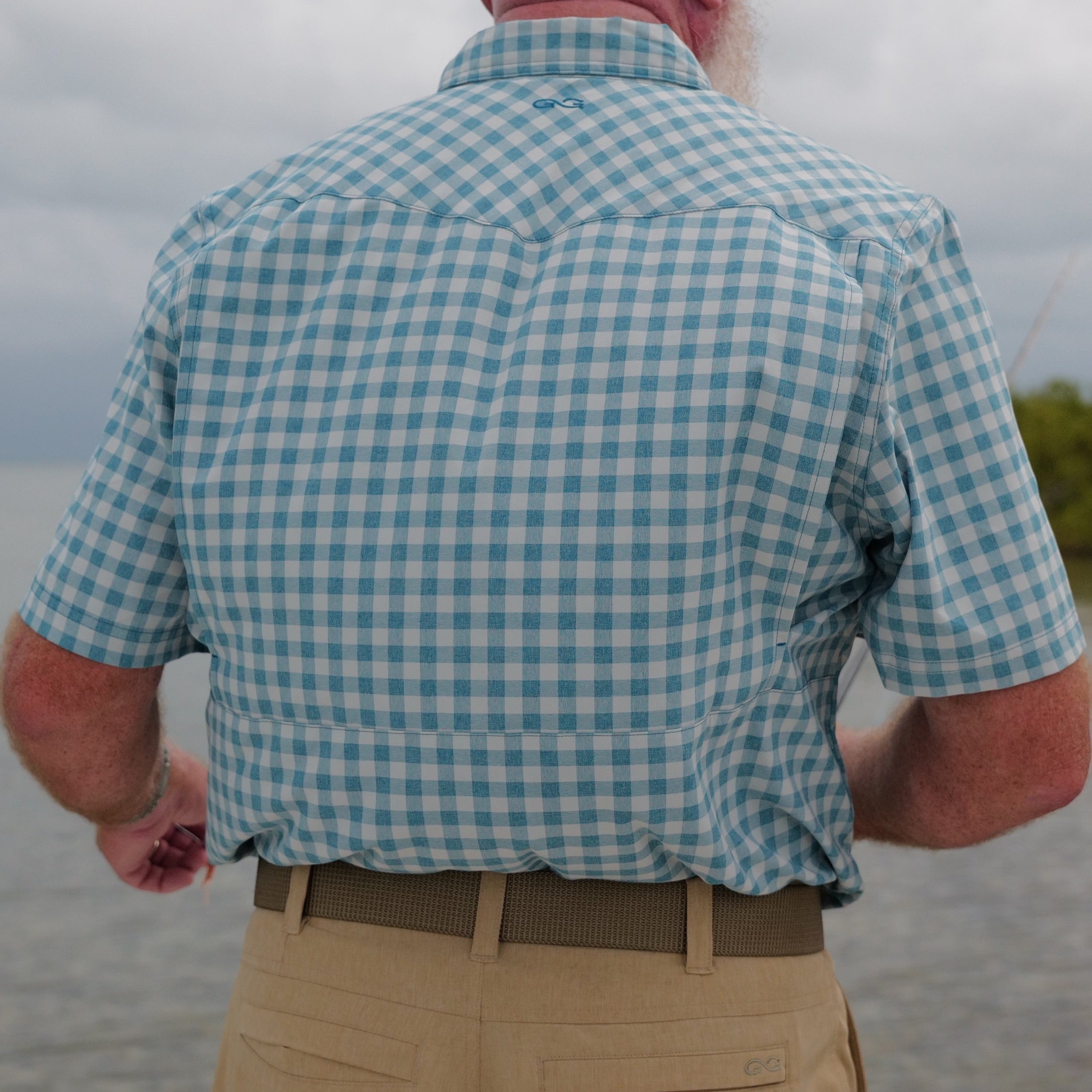 Person wearing a blue and white checkered shirt with a blurred background