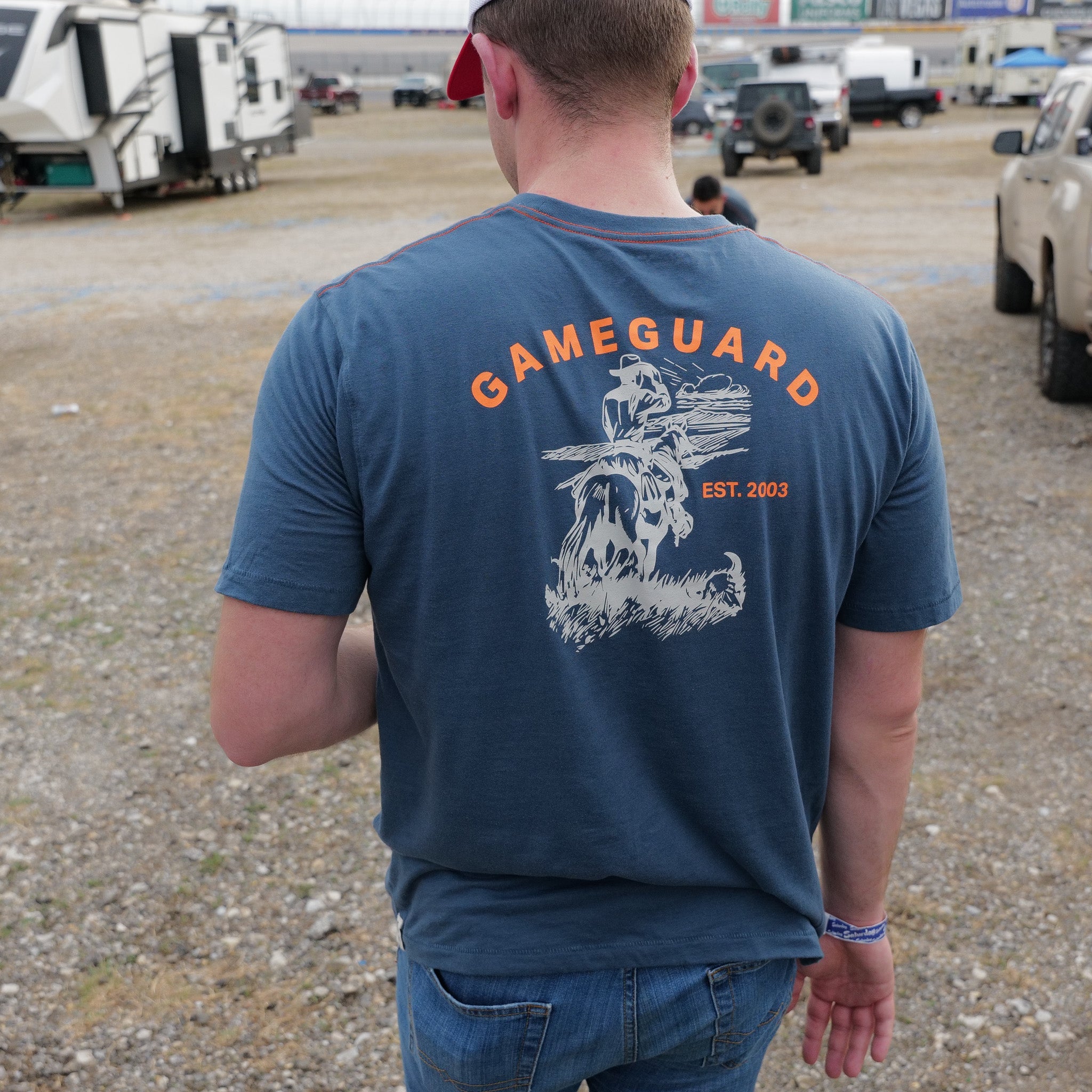 Man wearing a blue 'Gameguard' t-shirt with a logo in an outdoor setting.