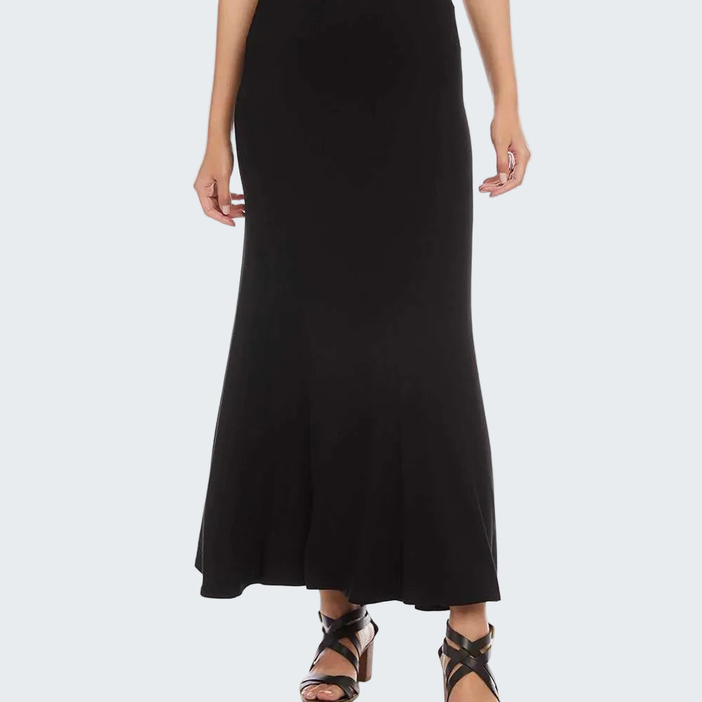 A woman modeling a long black skirt with a flared hem, paired with black strappy sandals against a plain white background.