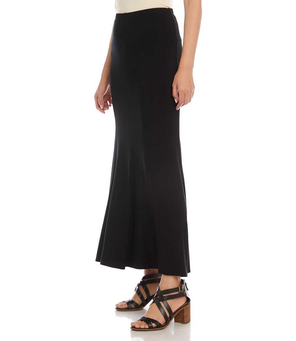 A model wearing a black high-waisted, flared midi skirt paired with black strappy heeled sandals, shown from the waist down on a white studio background.