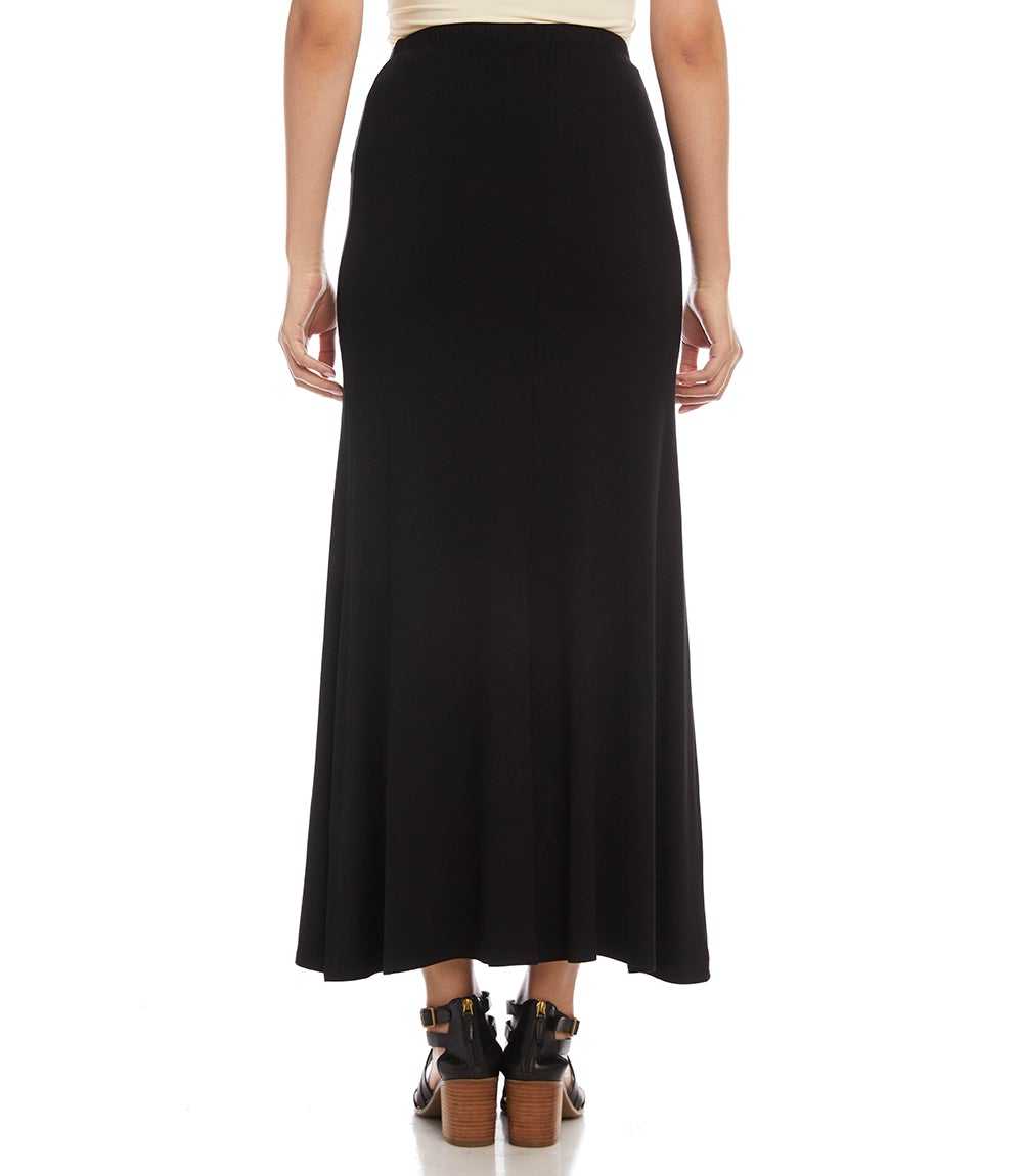 A woman shown from the back wearing a long black maxi skirt with a cream top and black heeled sandals, against a plain white background.