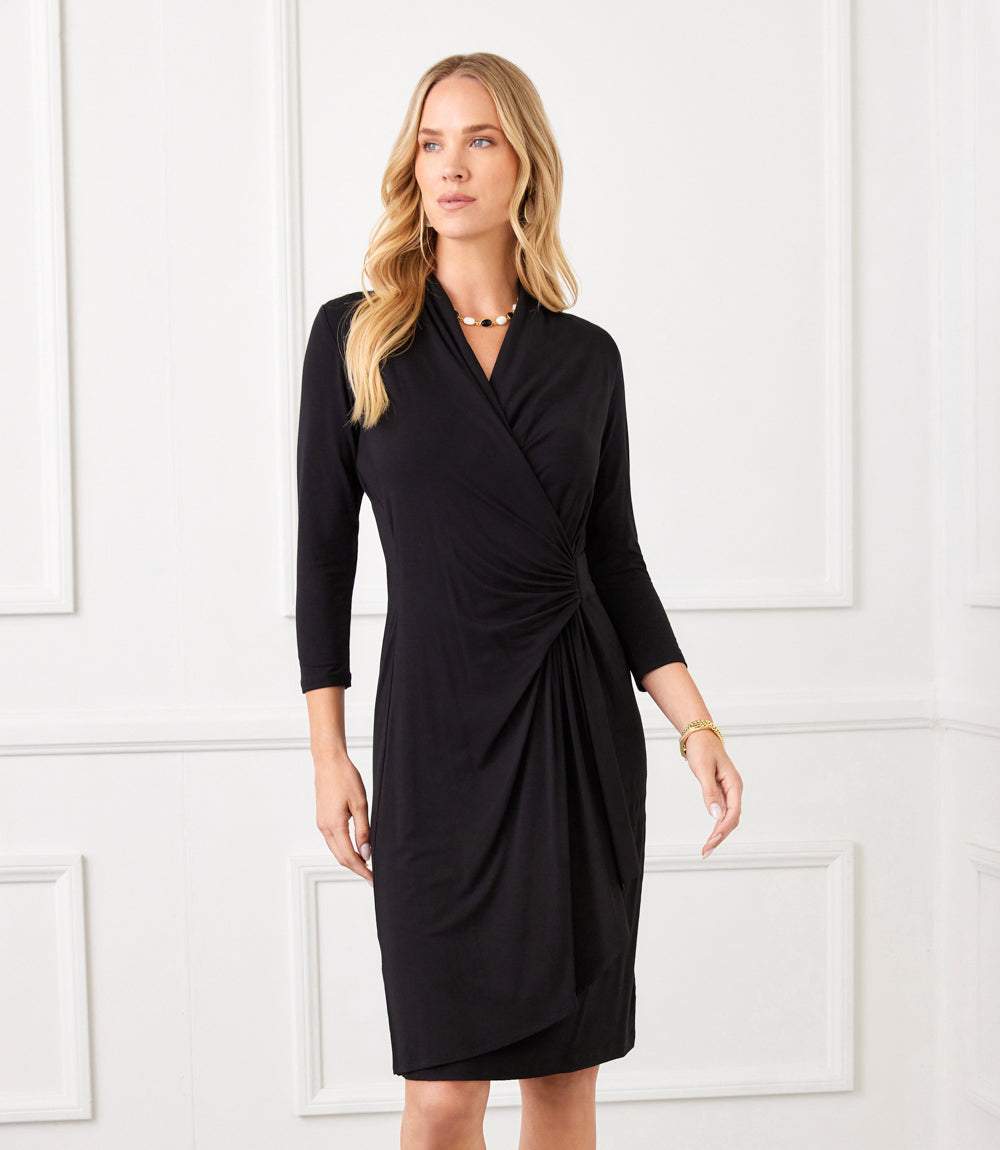Woman wearing a black dress against a white paneled wall