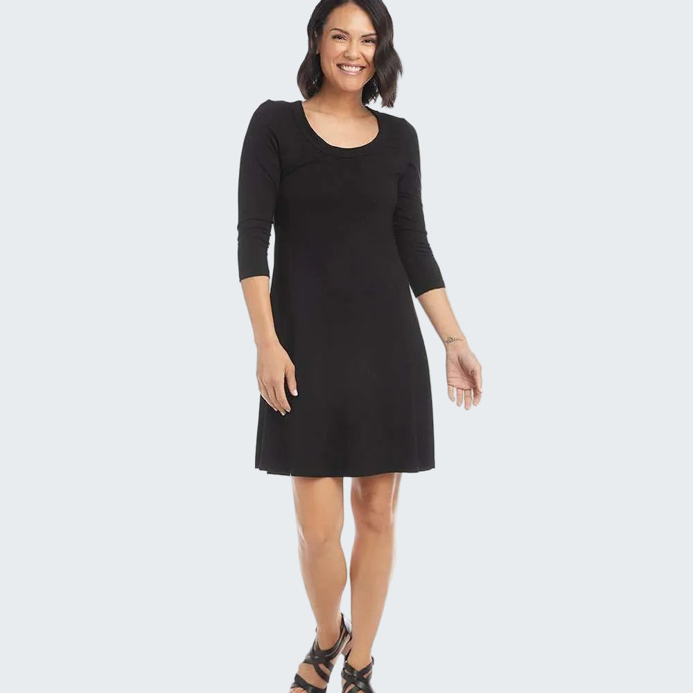 A woman modeling a black three-quarter sleeve shift dress with a scoop neckline, paired with black strappy high-heeled sandals, against a plain white background.