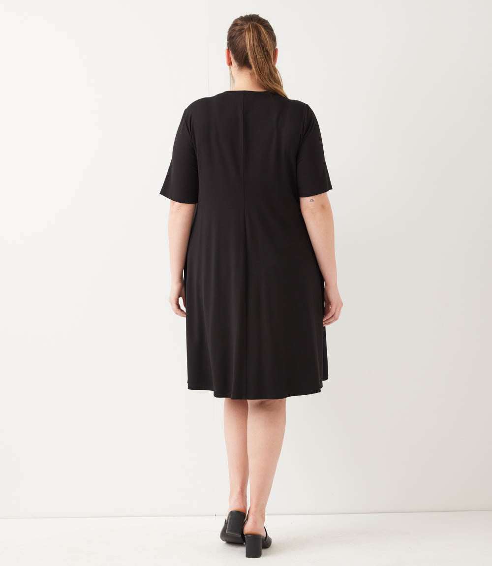 Person wearing a black dress against a white background