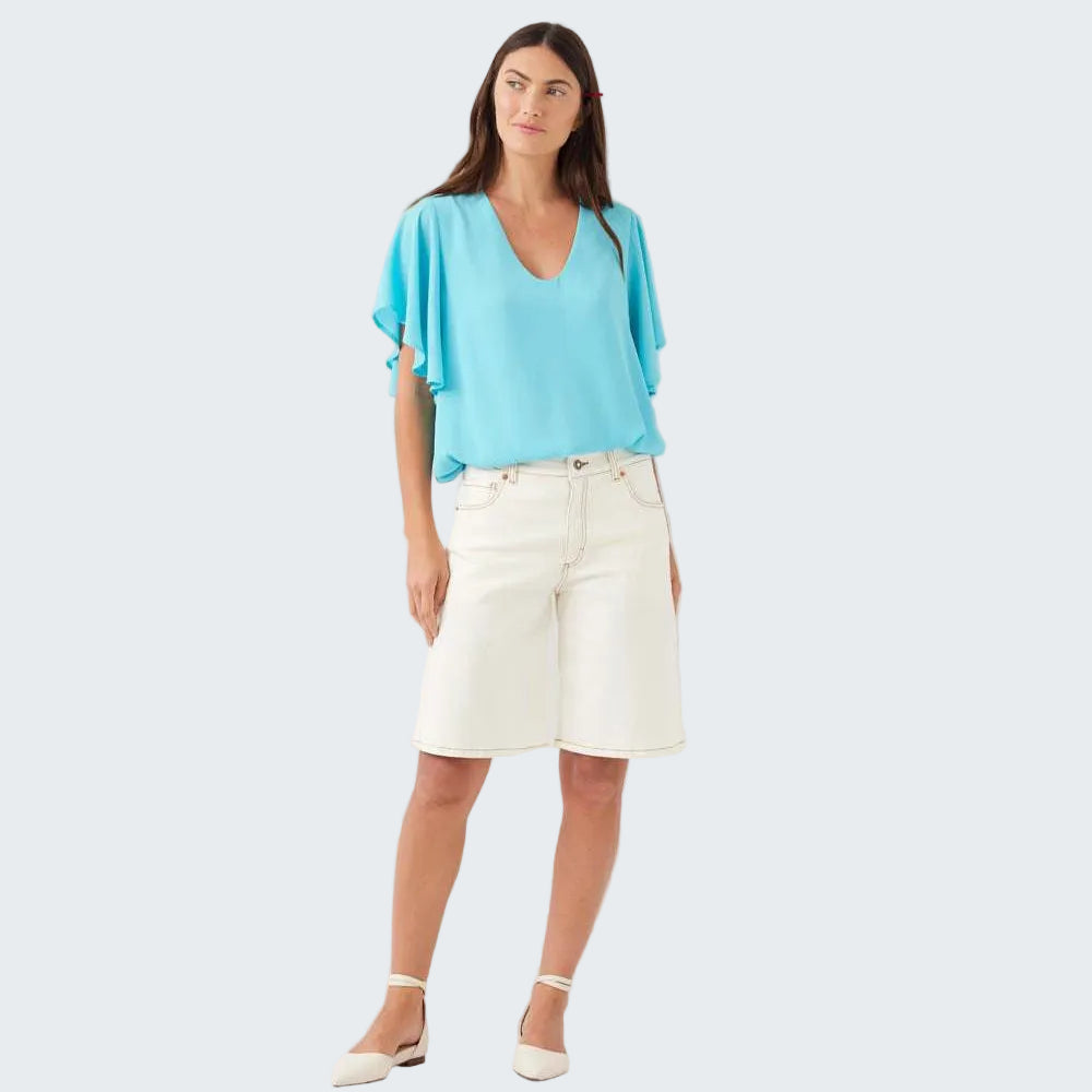 Woman wearing a light blue top and white shorts on a white background