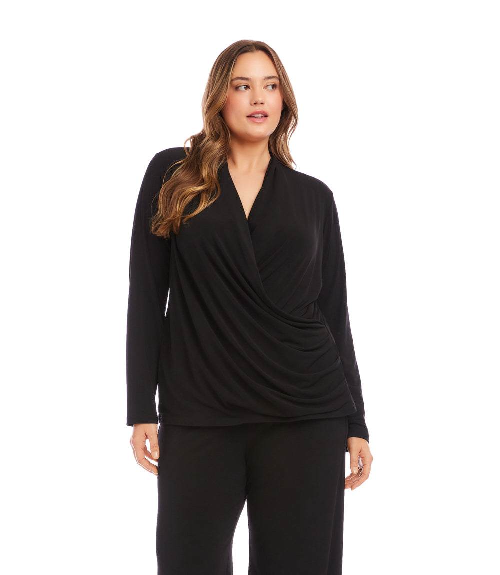 A woman modeling a black long-sleeve wrap-style top with a draped front, paired with black pants, against a plain white studio background.