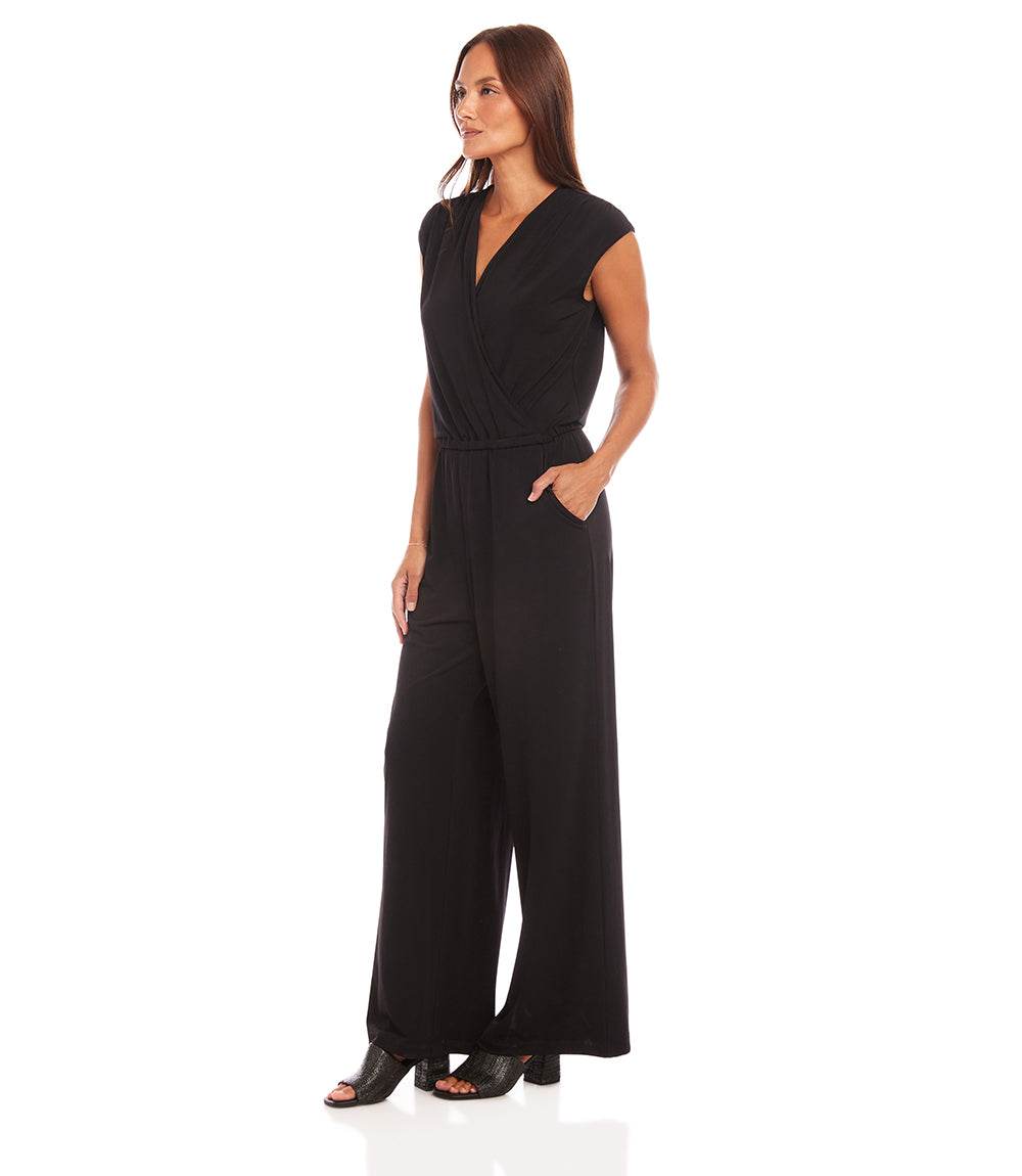 A woman modeling a black sleeveless wrap-style jumpsuit with wide legs and side pockets, photographed against a plain white studio background.