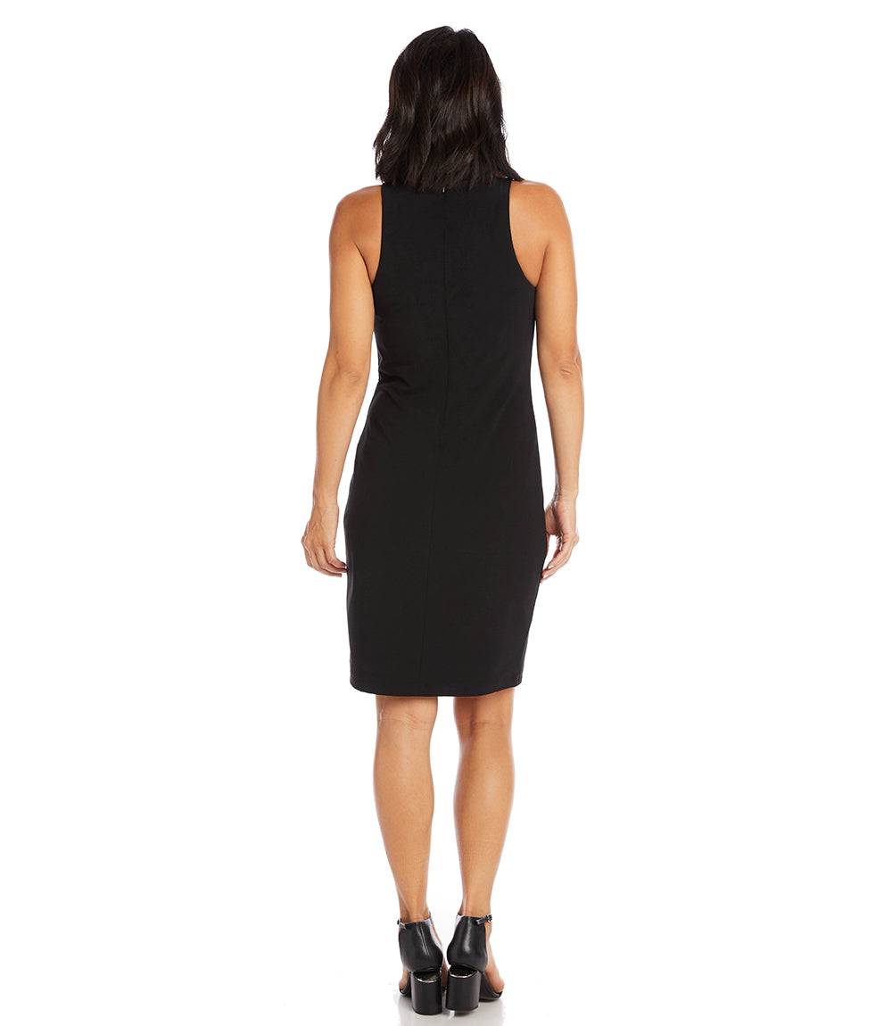 A woman viewed from the back wearing a sleeveless black knee-length dress and black high-heeled sandals against a plain white studio background.