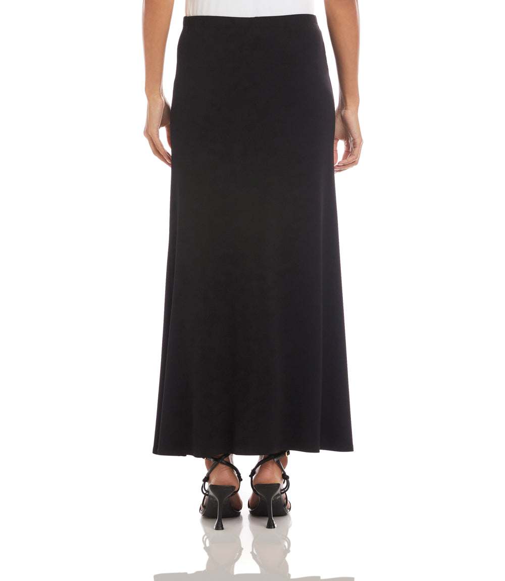 A black maxi skirt shown on a model from the back, paired with black strappy heels against a plain white background.