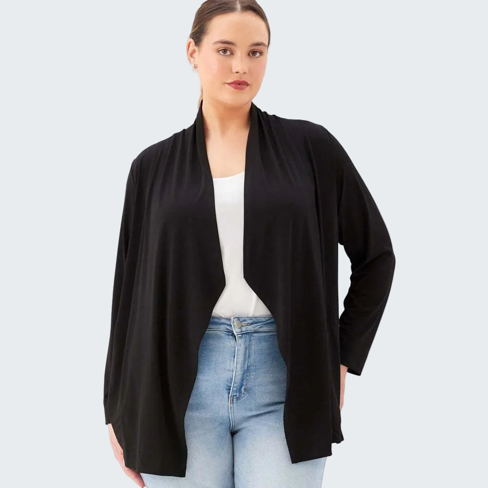 Woman wearing a black cardigan over a white top and blue jeans on a white background