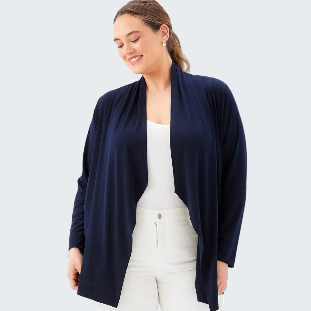 Woman wearing a navy cardigan over a white top and pants on a white background