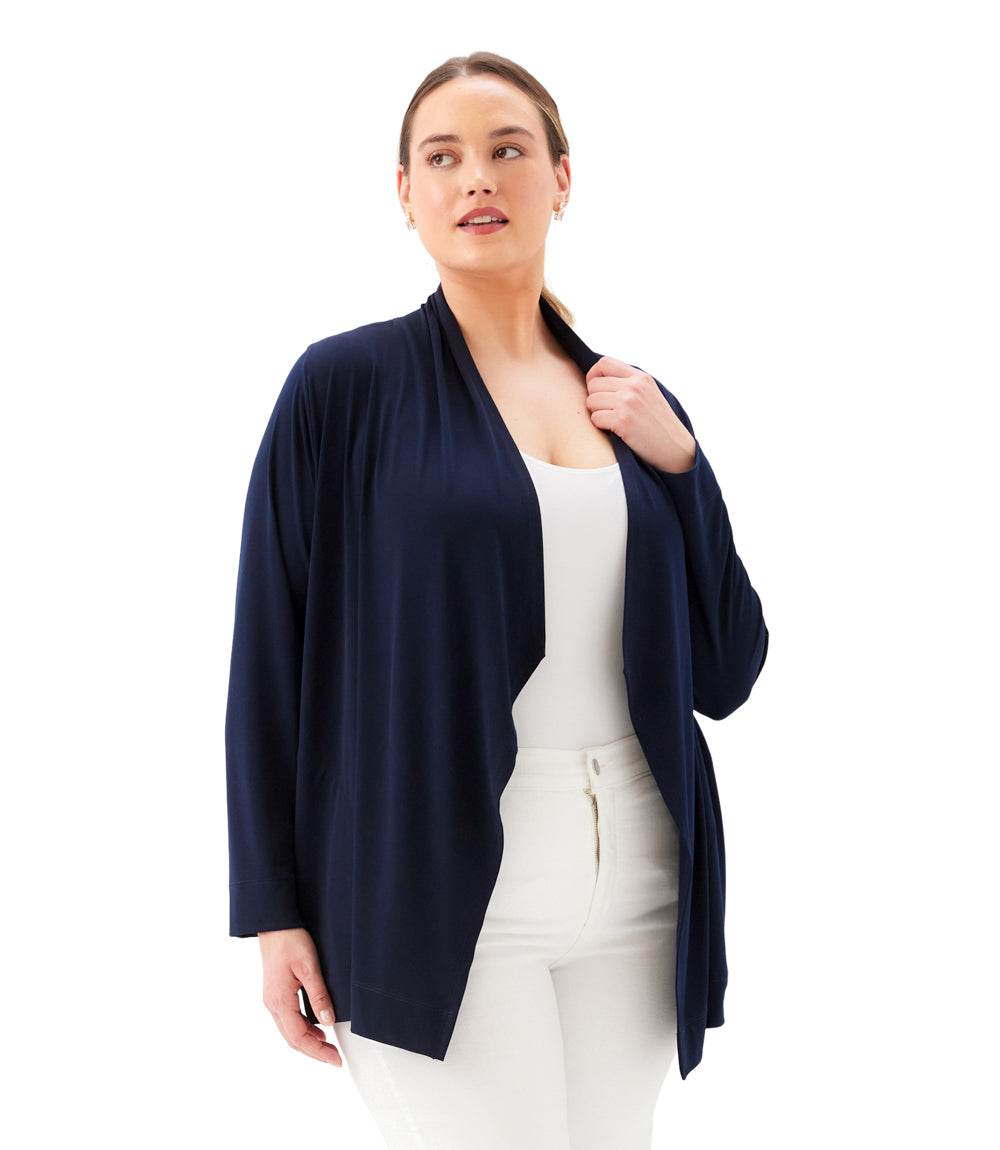 Woman wearing a navy cardigan over a white top and pants on a white background