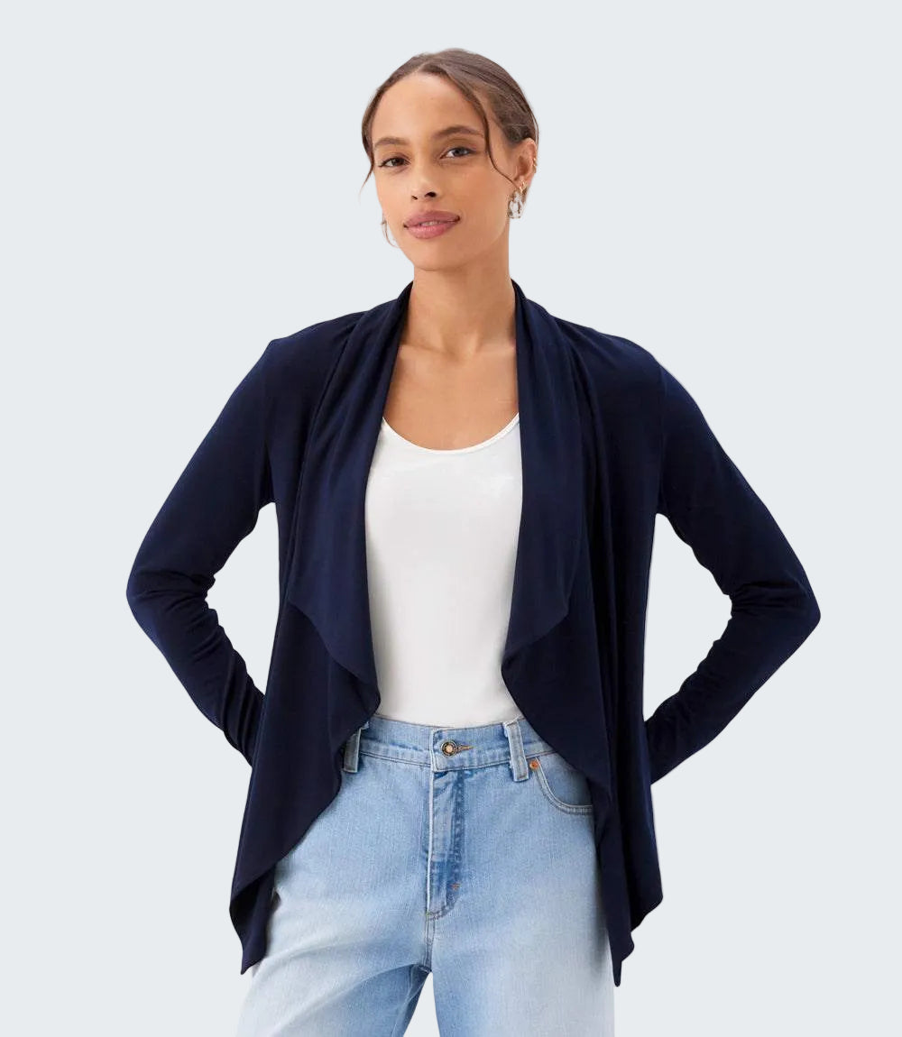 Woman wearing a navy cardigan over a white shirt and light blue jeans on a white background