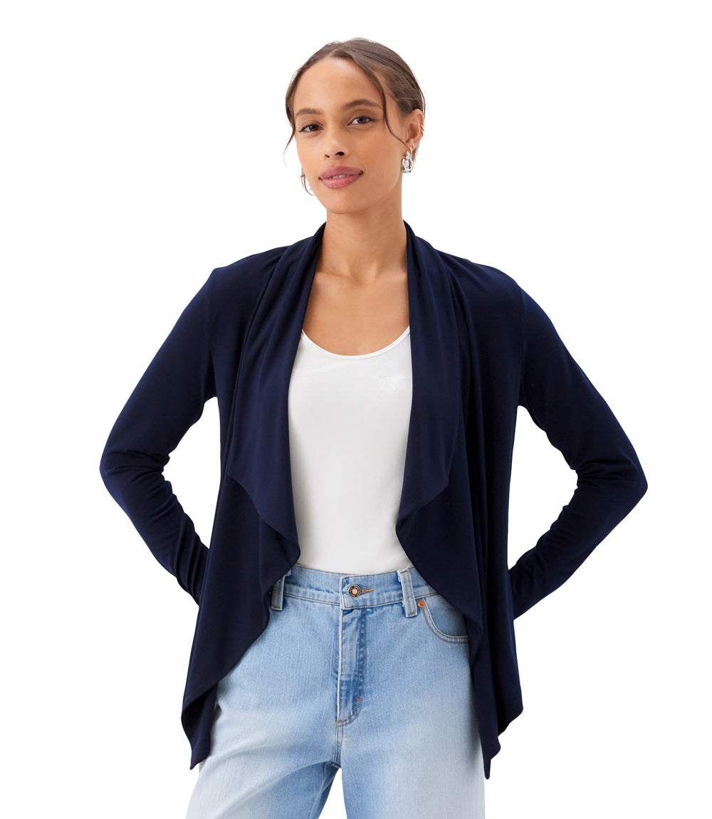 Woman wearing a navy cardigan over a white shirt and light blue jeans on a white background