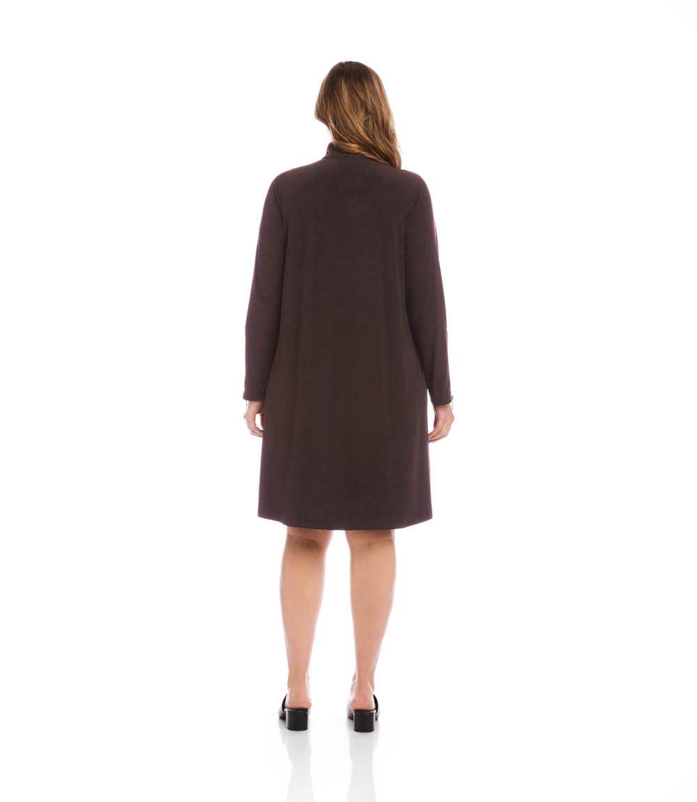 A woman viewed from the back wearing a dark brown long-sleeve knee-length coat or dress against a plain white studio background.