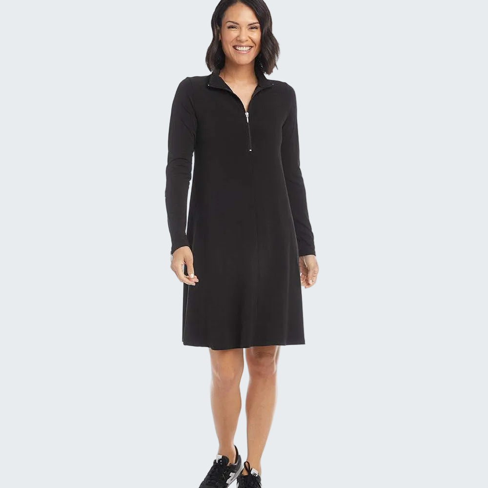 A woman modeling a black long-sleeve shift dress with a half-zip mock neck, standing against a plain white background.