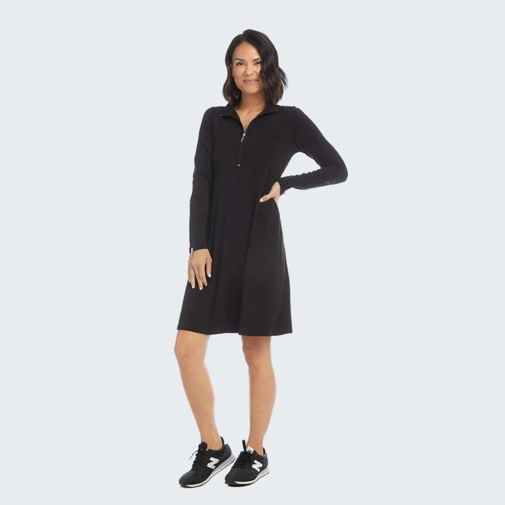 A woman modeling a black long-sleeve shift dress with a half-zip collar, paired with black sneakers, against a plain white studio background.