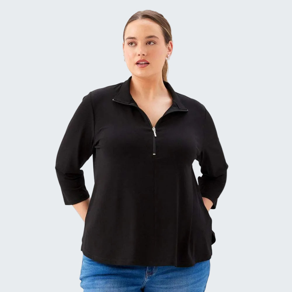 Woman wearing a black long-sleeve shirt with a quarter-zip and blue jeans on a white background