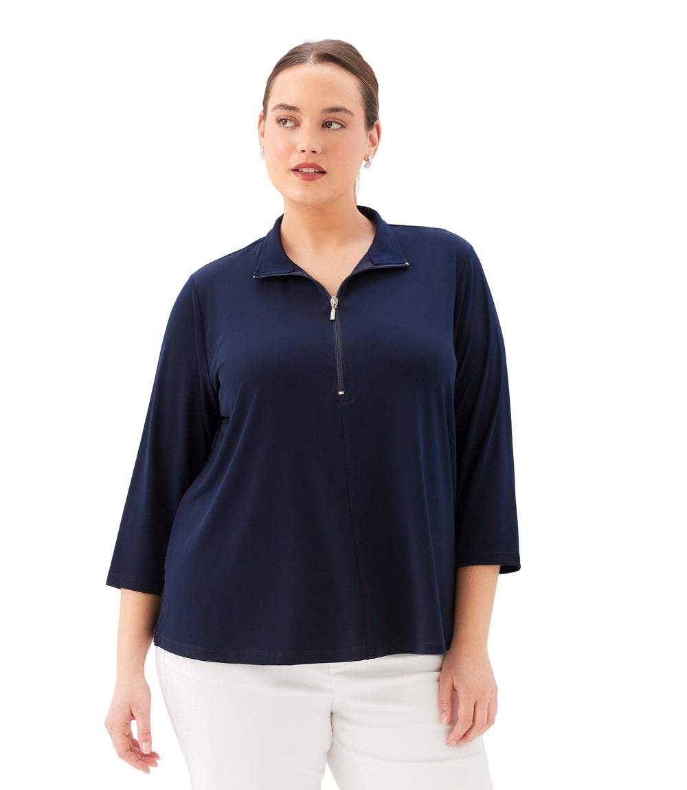 A woman modeling a navy blue three-quarter sleeve quarter-zip polo top with white pants, photographed against a solid white background.