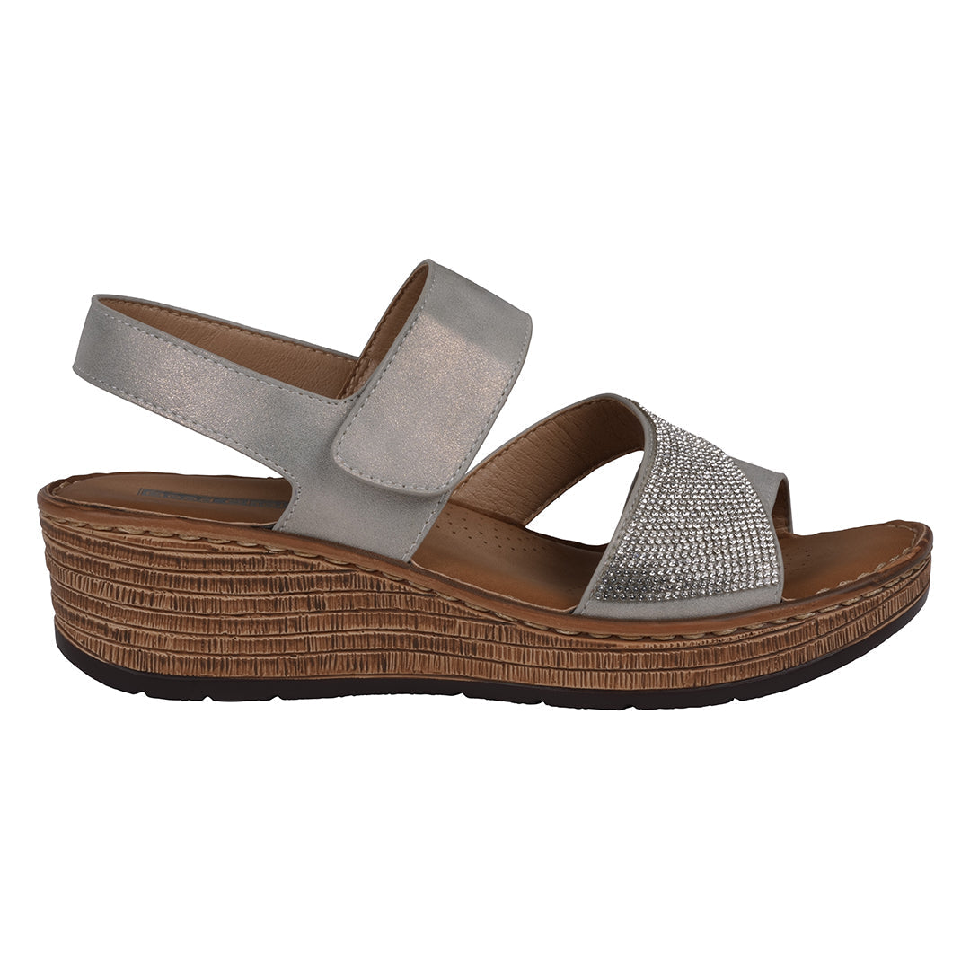 Wedge sandal with silver strap and brown sole on a white background