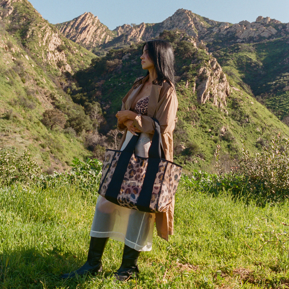 Woman holding a leopard print bag in a mountainous landscape