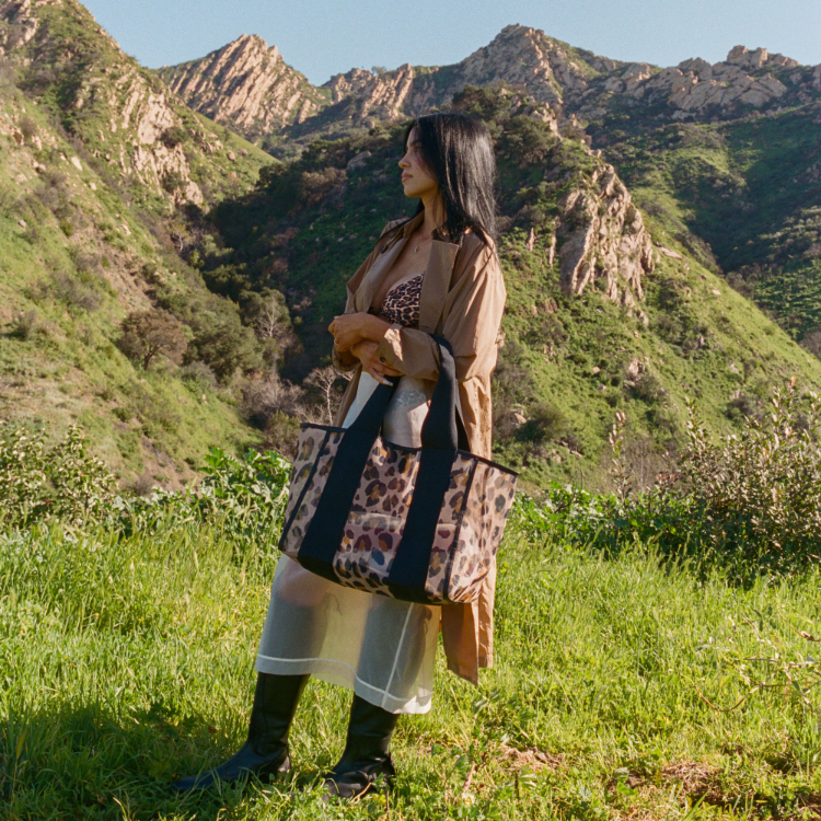 Woman holding a leopard print bag in a mountainous landscape