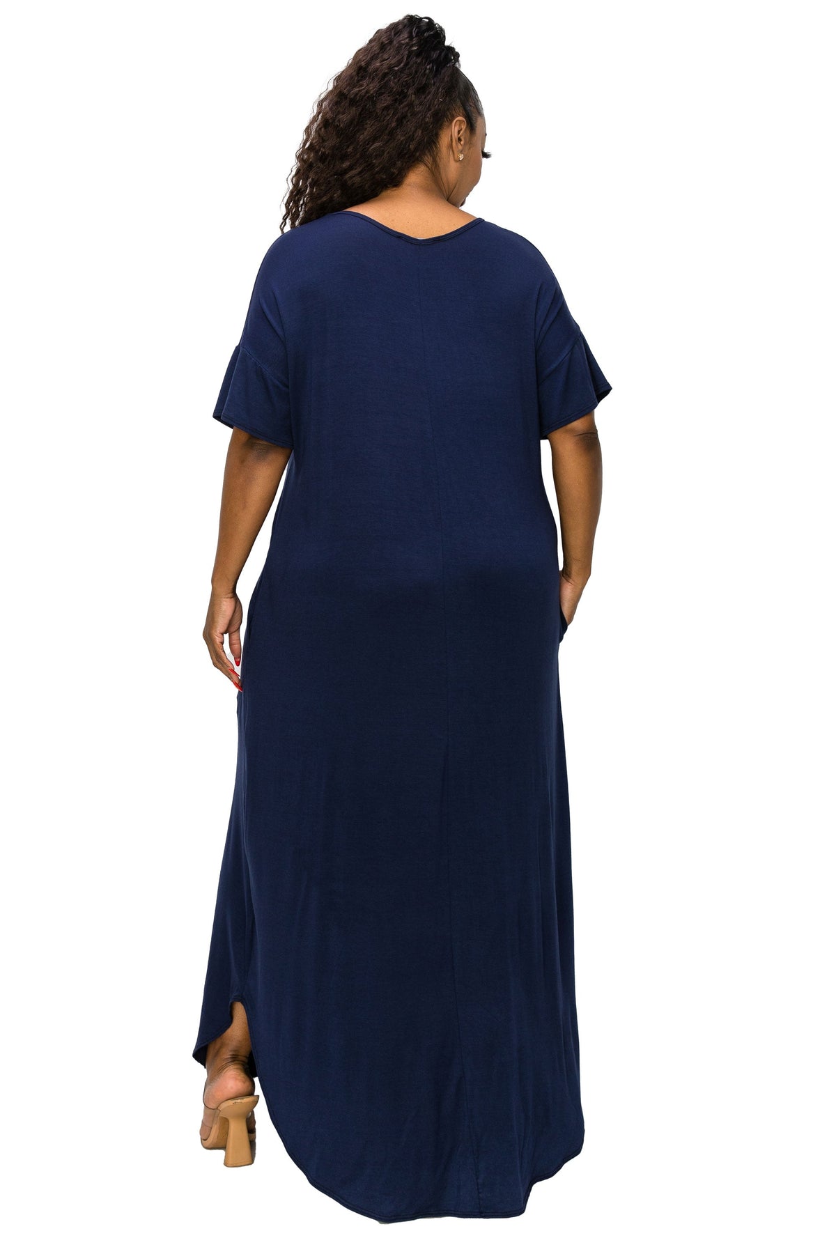 A woman viewed from the back wearing a loose, short-sleeve navy maxi dress with side slits, standing against a plain white background.