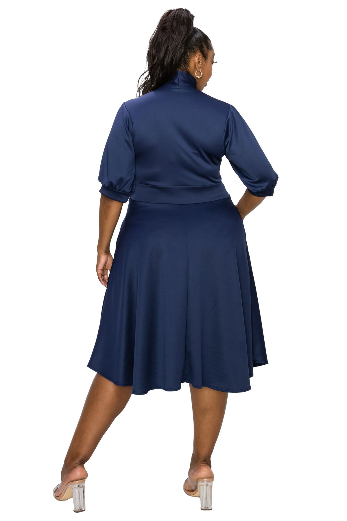 A woman modeling a navy blue satin-like dress from the back, featuring three-quarter puffed sleeves and a flared knee-length skirt, set against a plain white background.