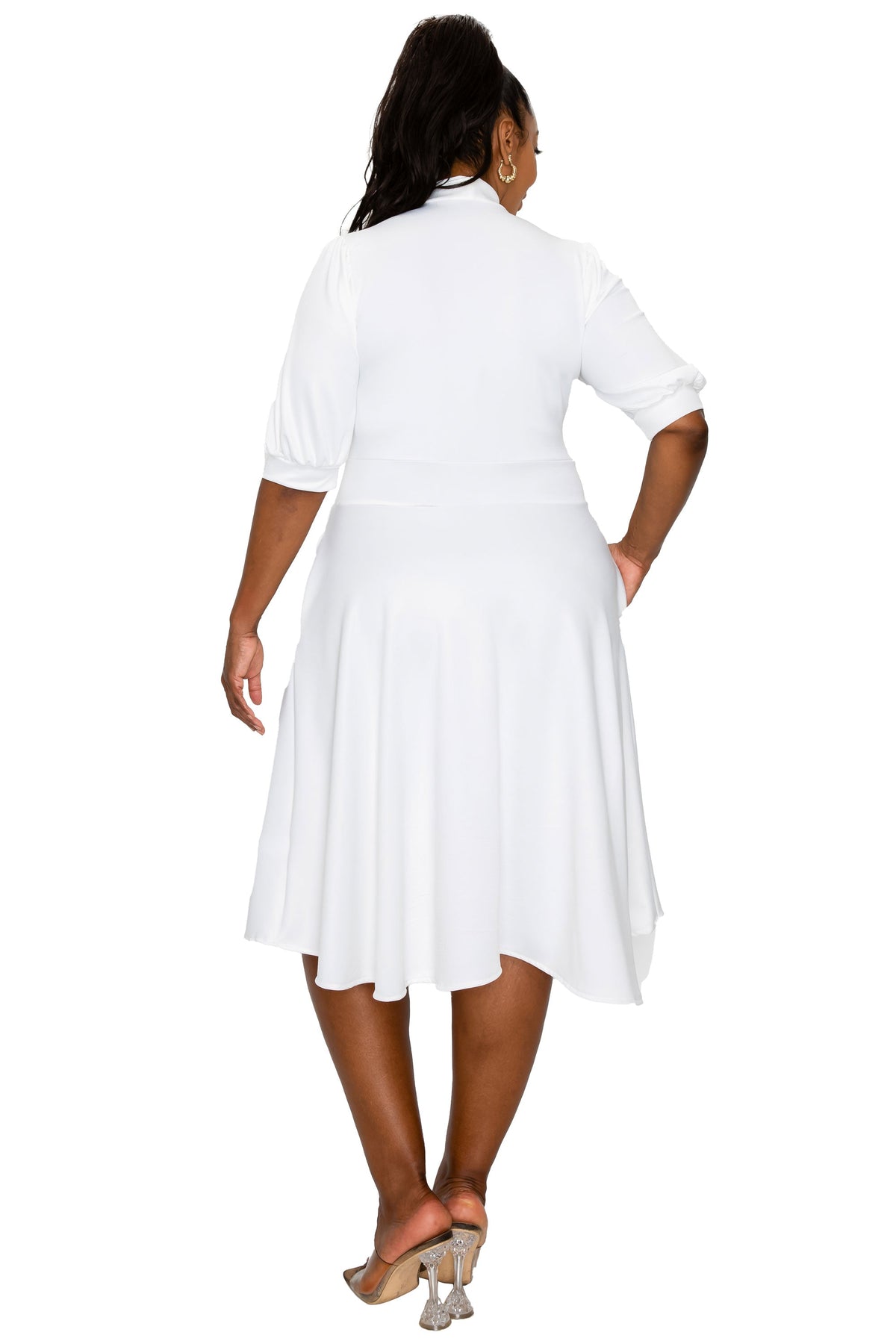 A woman shown from the back wearing a white midi dress with three-quarter sleeves and a flared skirt, paired with beige high-heeled sandals, against a plain white background.