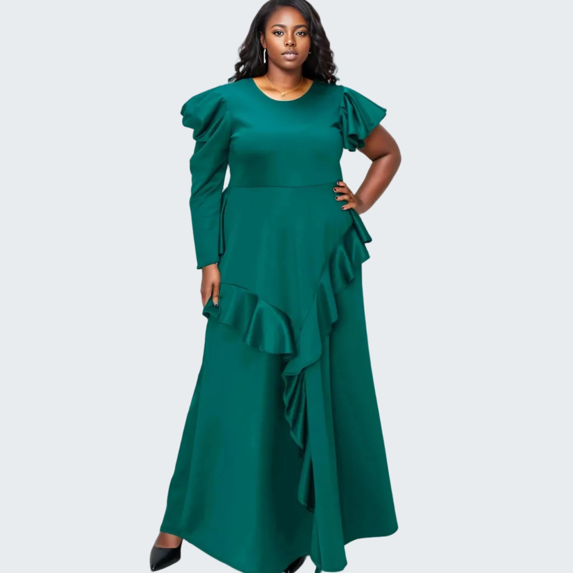 A woman modeling a floor-length emerald green dress with dramatic ruffled sleeves and layered ruffles along the skirt, photographed against a plain white background.