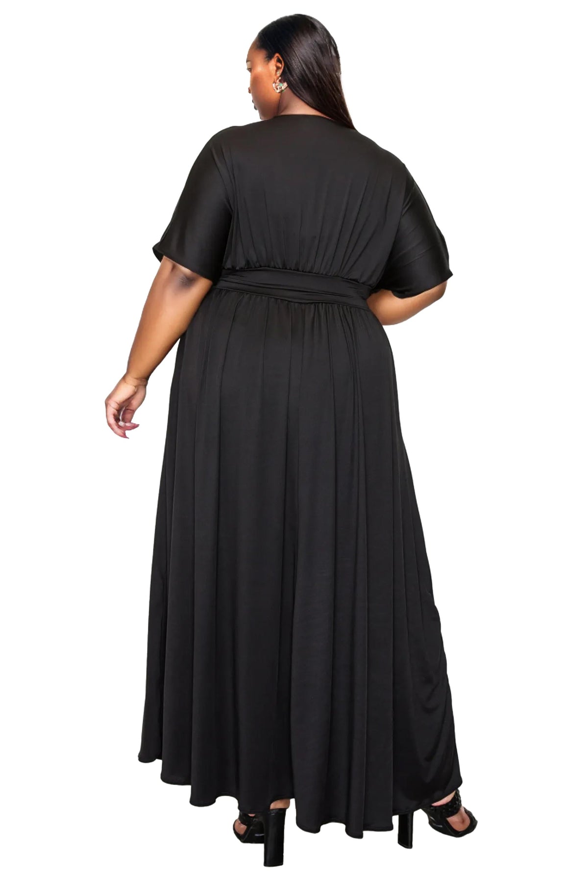A plus-size woman shown from the back wearing a black short-sleeve maxi dress with a gathered waist, paired with black high heels, against a plain white background.
