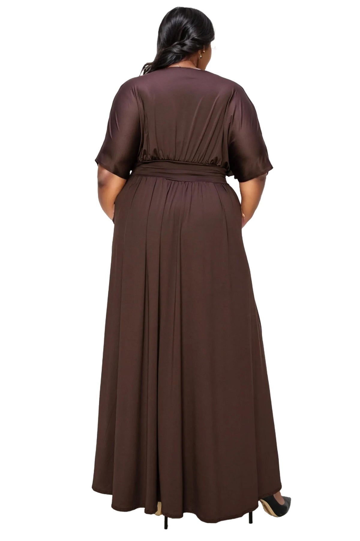 A woman viewed from the back wearing a long brown dress with short sleeves and a matching belt, photographed against a plain white background.