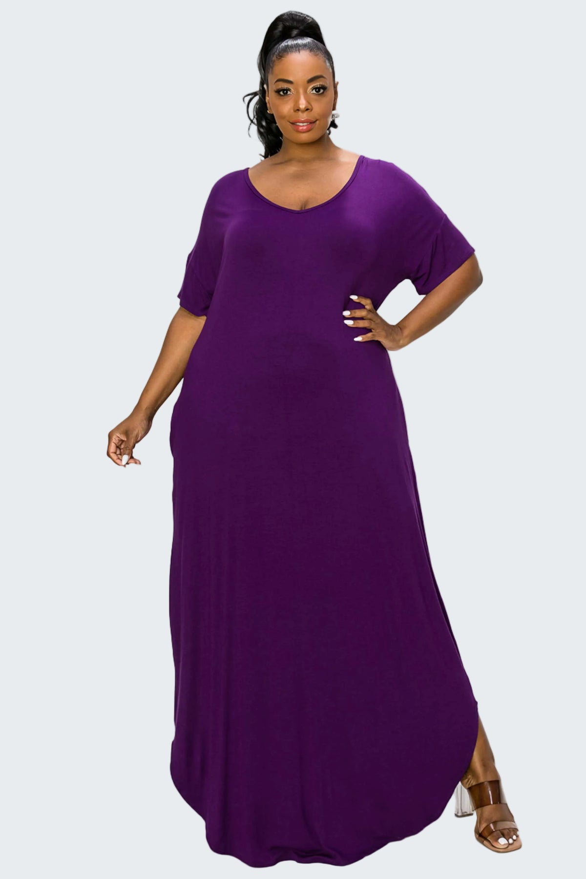 A woman modeling a purple short-sleeve maxi dress with a scoop neckline, photographed against a plain white background.