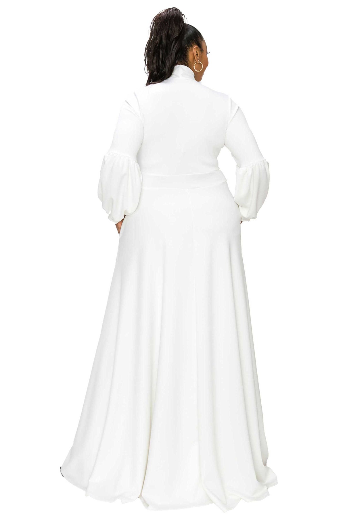 A woman shown from the back wearing a long white dress with a high mock neck, structured shoulders, and voluminous puffed sleeves, photographed against a plain white studio background.