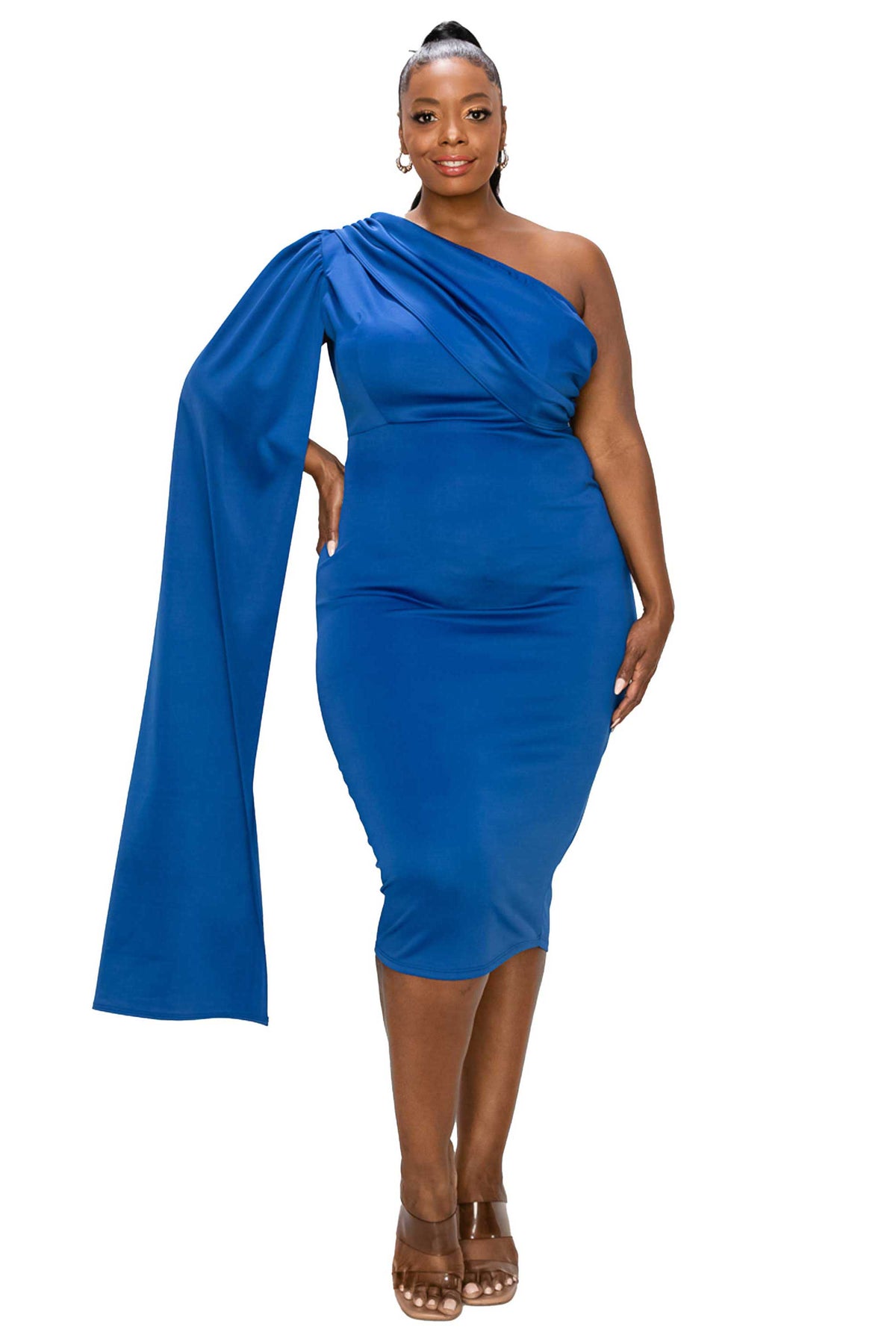 A woman modeling a royal blue one-shoulder midi dress with a dramatic draped sleeve and fitted silhouette, paired with brown strappy heels against a plain white background.