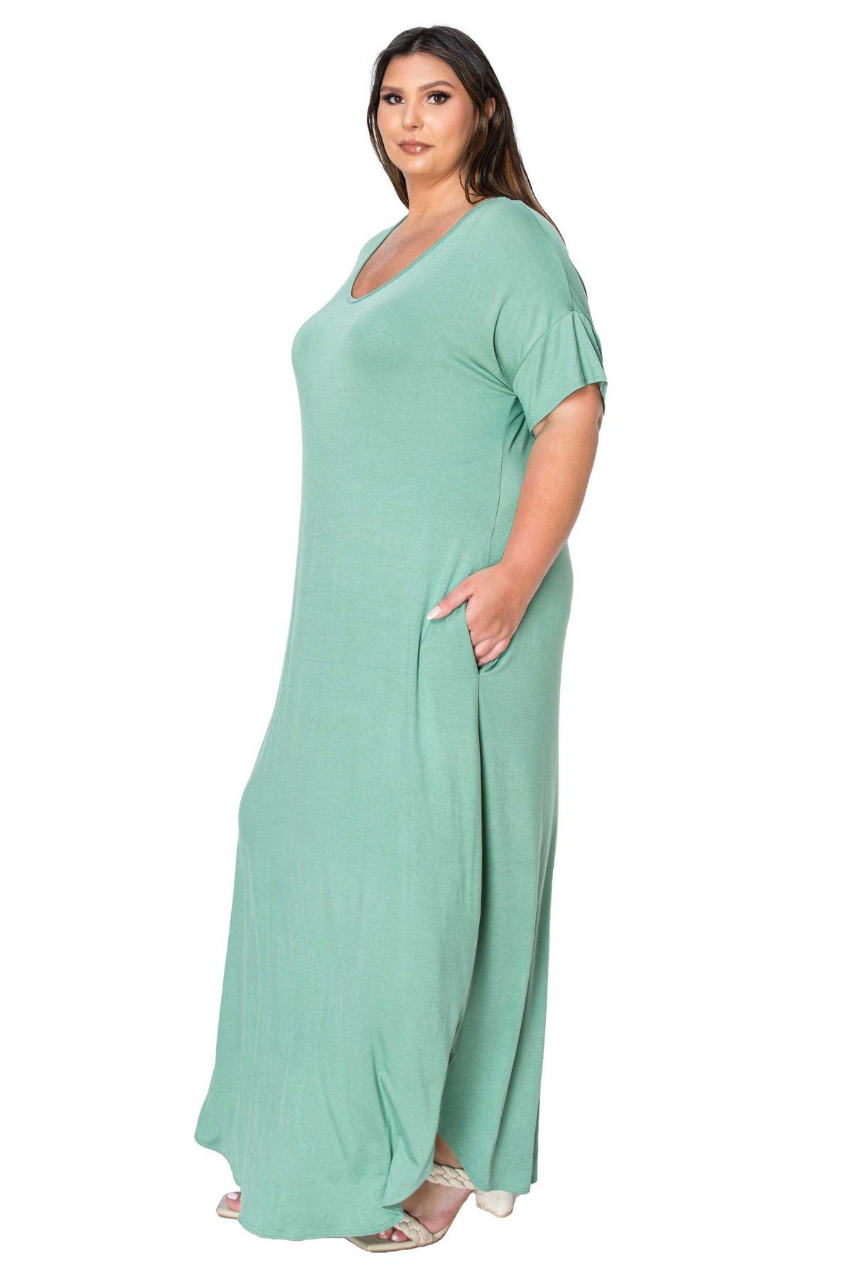 A woman modeling a sage green maxi dress with short sleeves, a V-neckline, and side pockets, set against a plain white background.