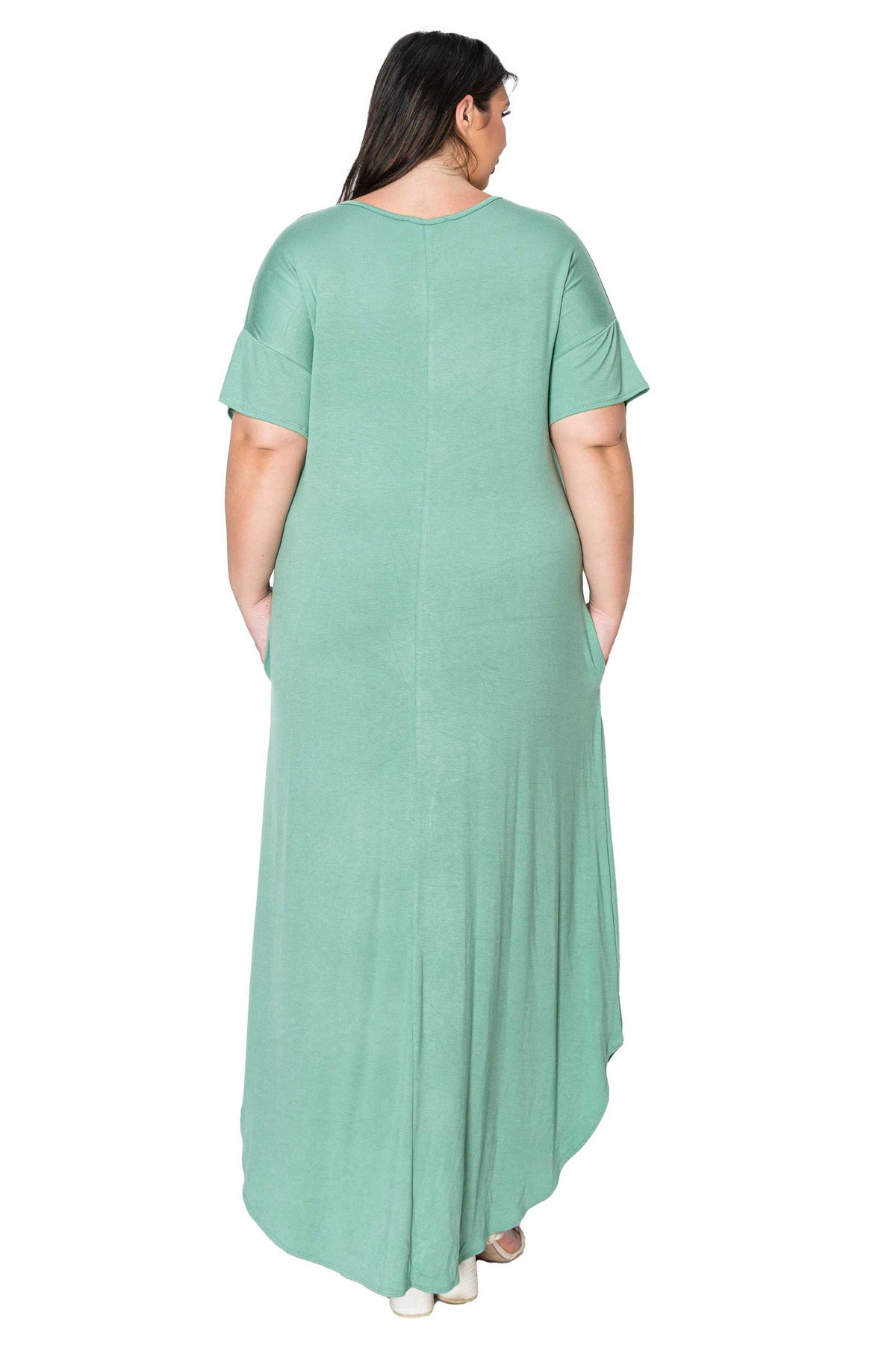 A woman viewed from the back wearing a sage green short-sleeve maxi dress with side pockets, set against a plain white background.