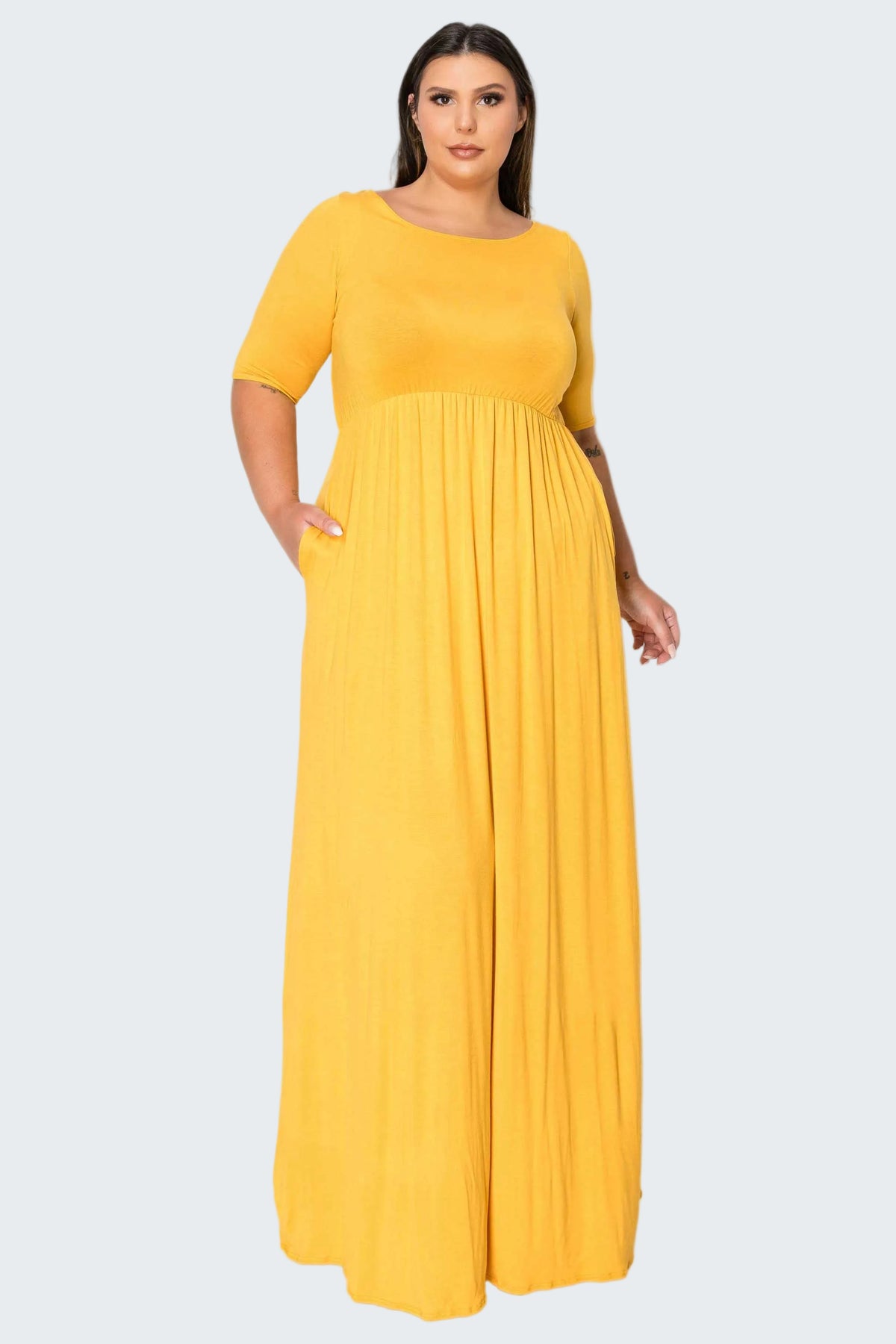 A woman modeling a bright yellow, short-sleeved maxi dress with a pleated skirt against a plain white background.