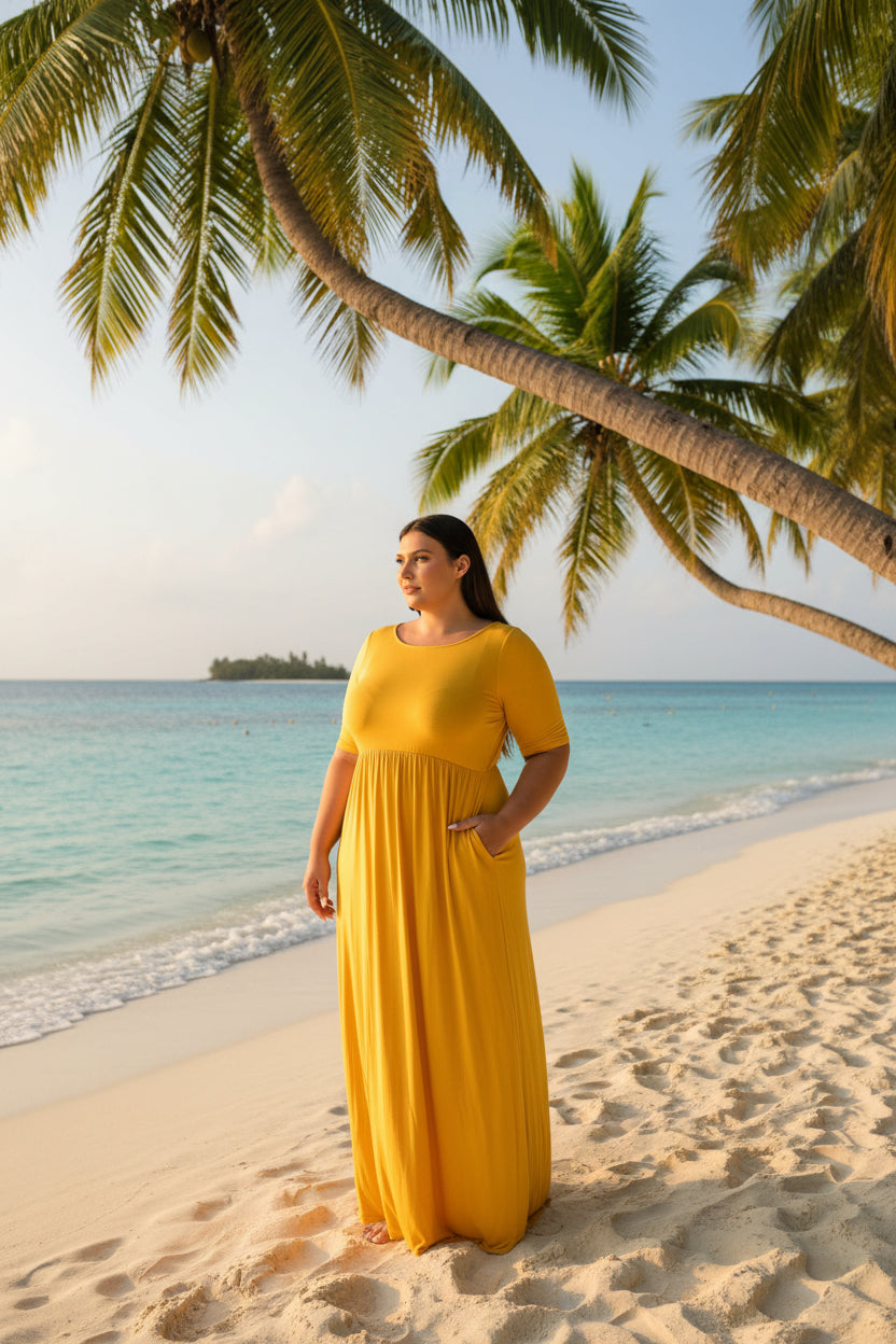 A woman modeling a bright yellow, floor-length maxi dress with short sleeves and side pockets against a plain white background.