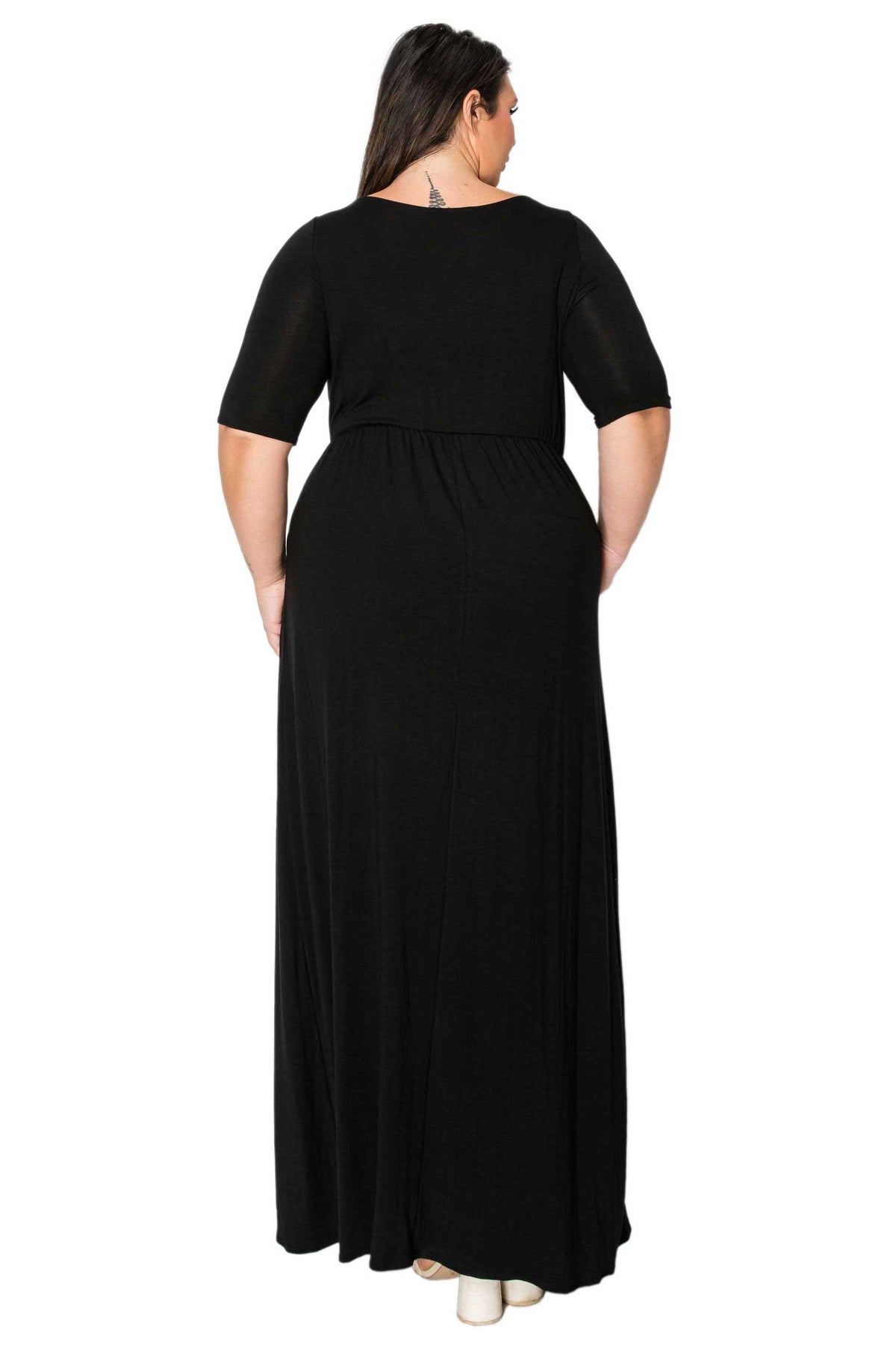 A woman viewed from the back wearing a black short-sleeve maxi dress with a gathered waist, set against a plain white background.
