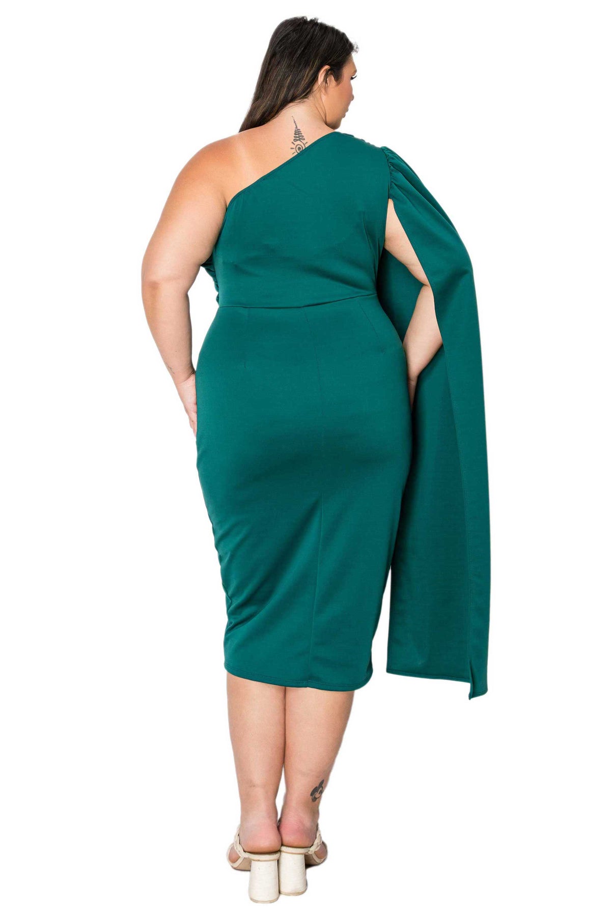 A woman modeling a one-shoulder emerald green midi dress from the back, featuring a draped capelet detail over one shoulder, set against a plain white background.