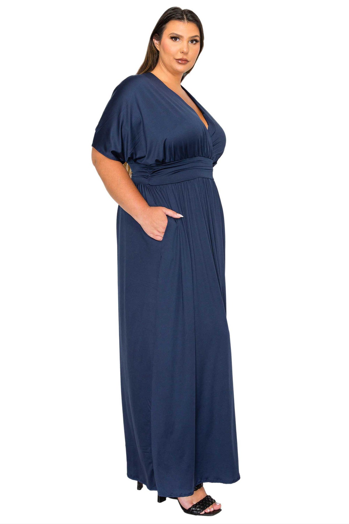 A woman modeling a navy blue maxi dress with short flutter sleeves, a deep V-neckline, and side pockets, set against a plain white background.