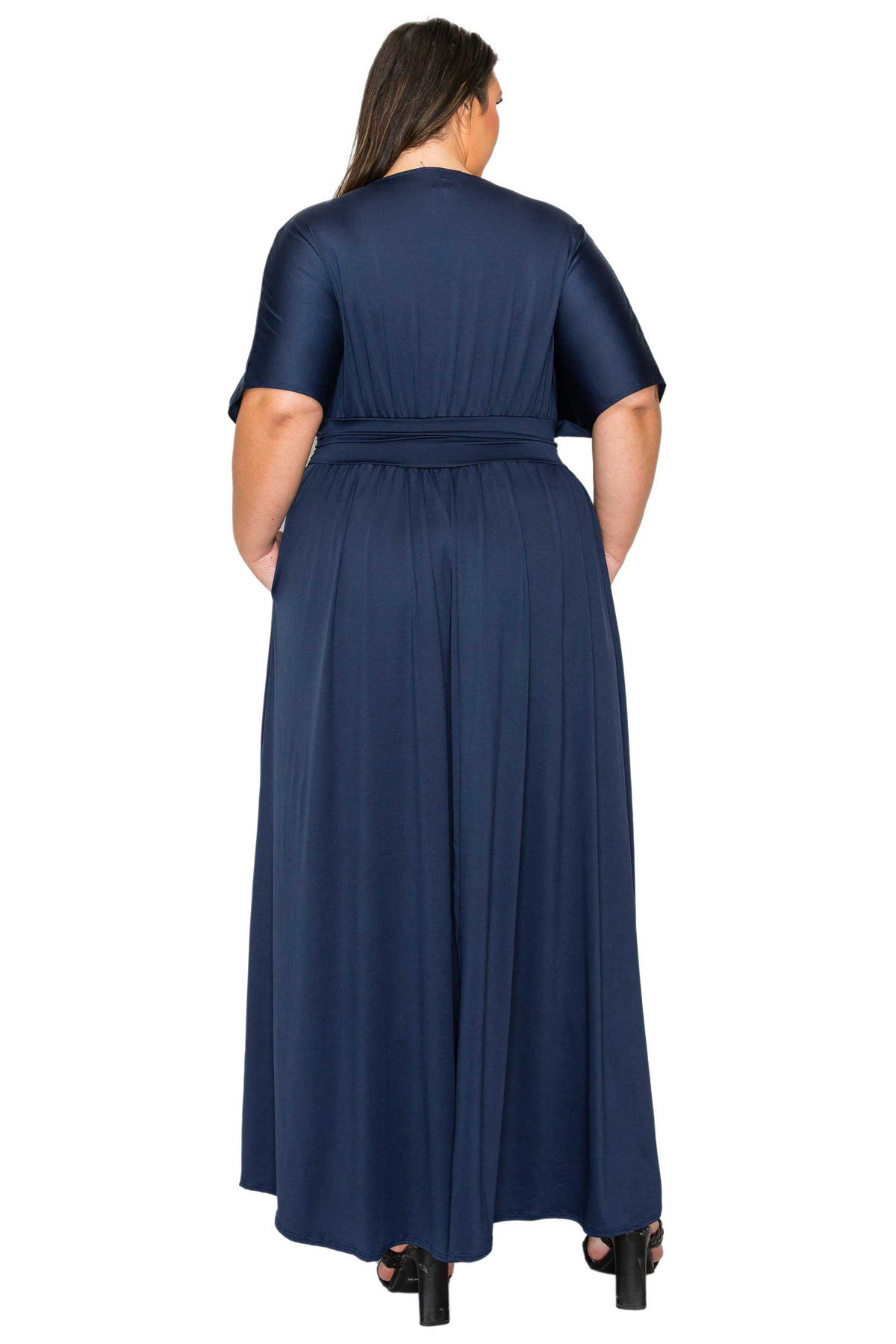 A woman viewed from the back wearing a navy blue short-sleeve maxi dress with a matching waist tie, set against a plain white background.
